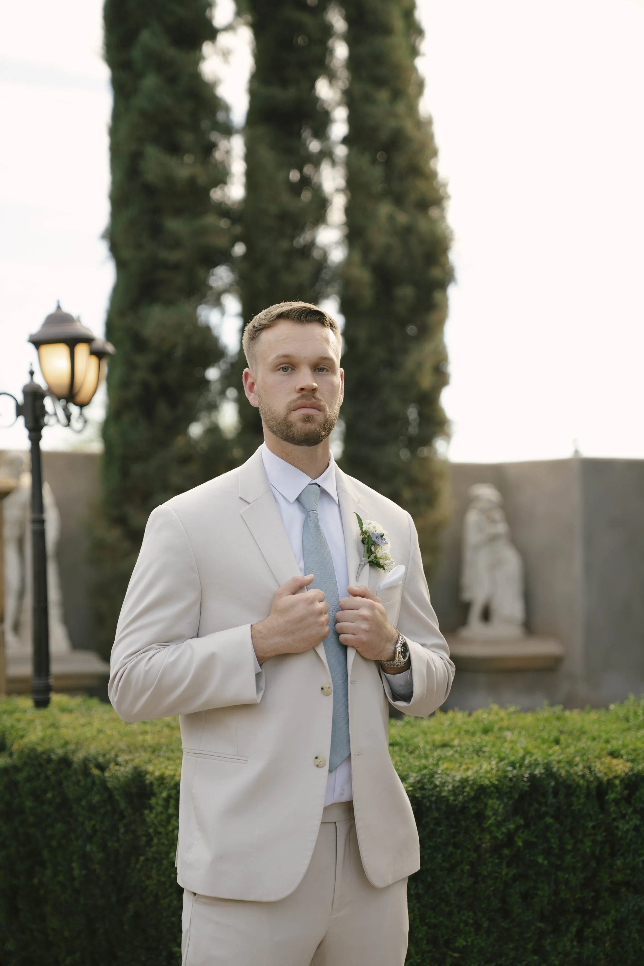 The groom’s portraits at Ashley Castle in Chandler, Arizona, were captured through hybrid film and digital photography, highlighting timeless style, refined details, and elegant garden backdrops that complement the venue’s romantic castle setting.