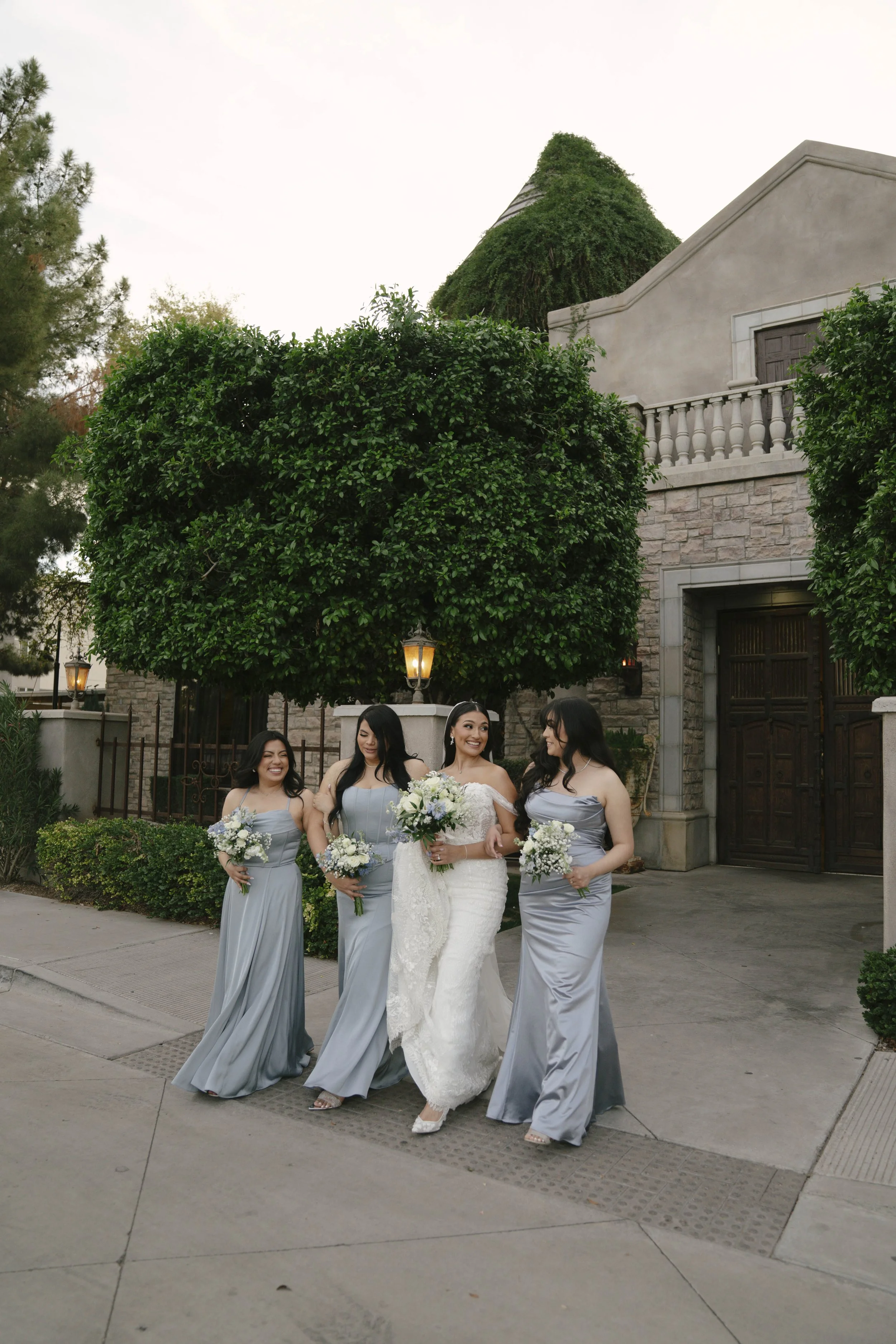 Bridal portraits at Ashley Castle in Chandler, Arizona, were captured through hybrid film and digital photography, showcasing the bride’s timeless elegance alongside her bridesmaids in the castle’s romantic courtyard gardens with soft evening light a