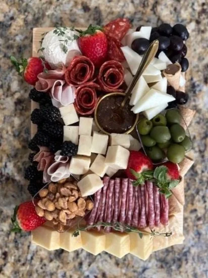 Charcuterie board with strawberries, blackberries, grapes, cheese cubes, salami, walnuts, honey, and berries.