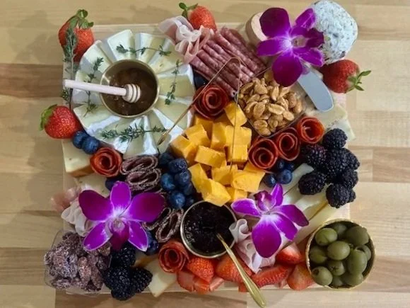 Fruit and cheese platter with meats, olives, and orchids