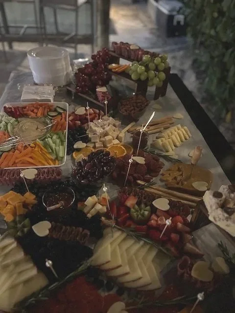 A charcuterie board with assorted cheeses, grapes, strawberries, and various meats on a table.