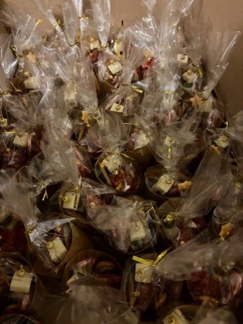 A large pile of small gift bags filled with assorted treats, each tied with a gold twist tie, arranged in a chaotic manner.