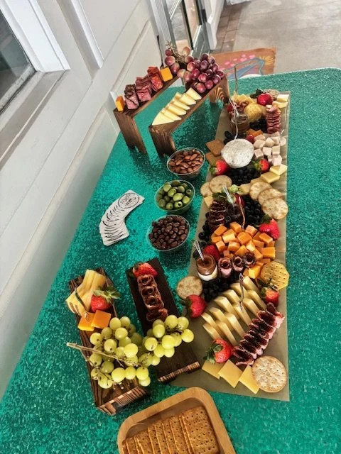 Snack board with cheese, crackers, chocolate, and grapes