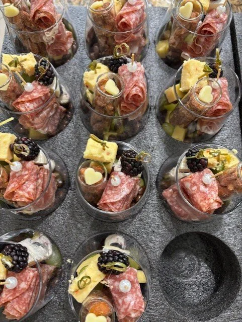 Individual charcuterie cups with meats, cheeses, grapes, blackberries, and small toppings.