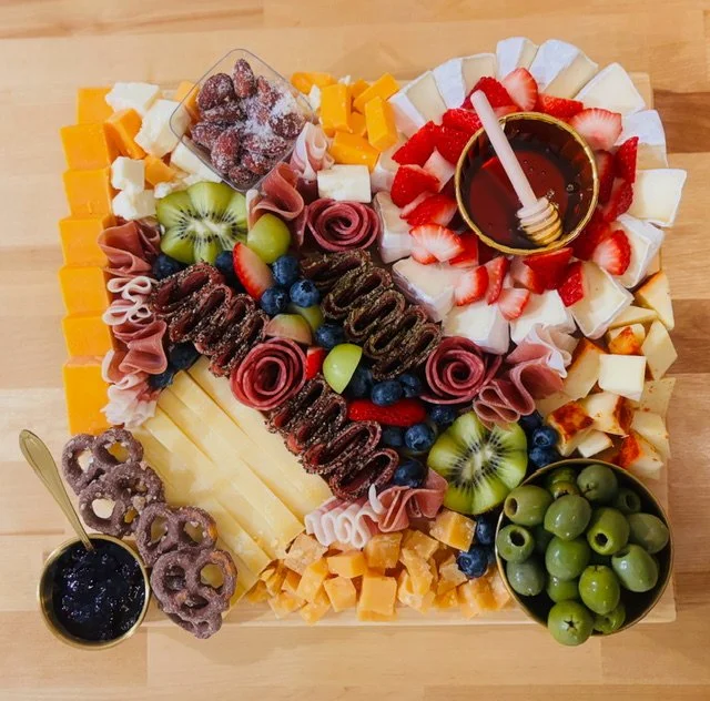Large fruit and cheese board with chocolates and sliced cheeses.