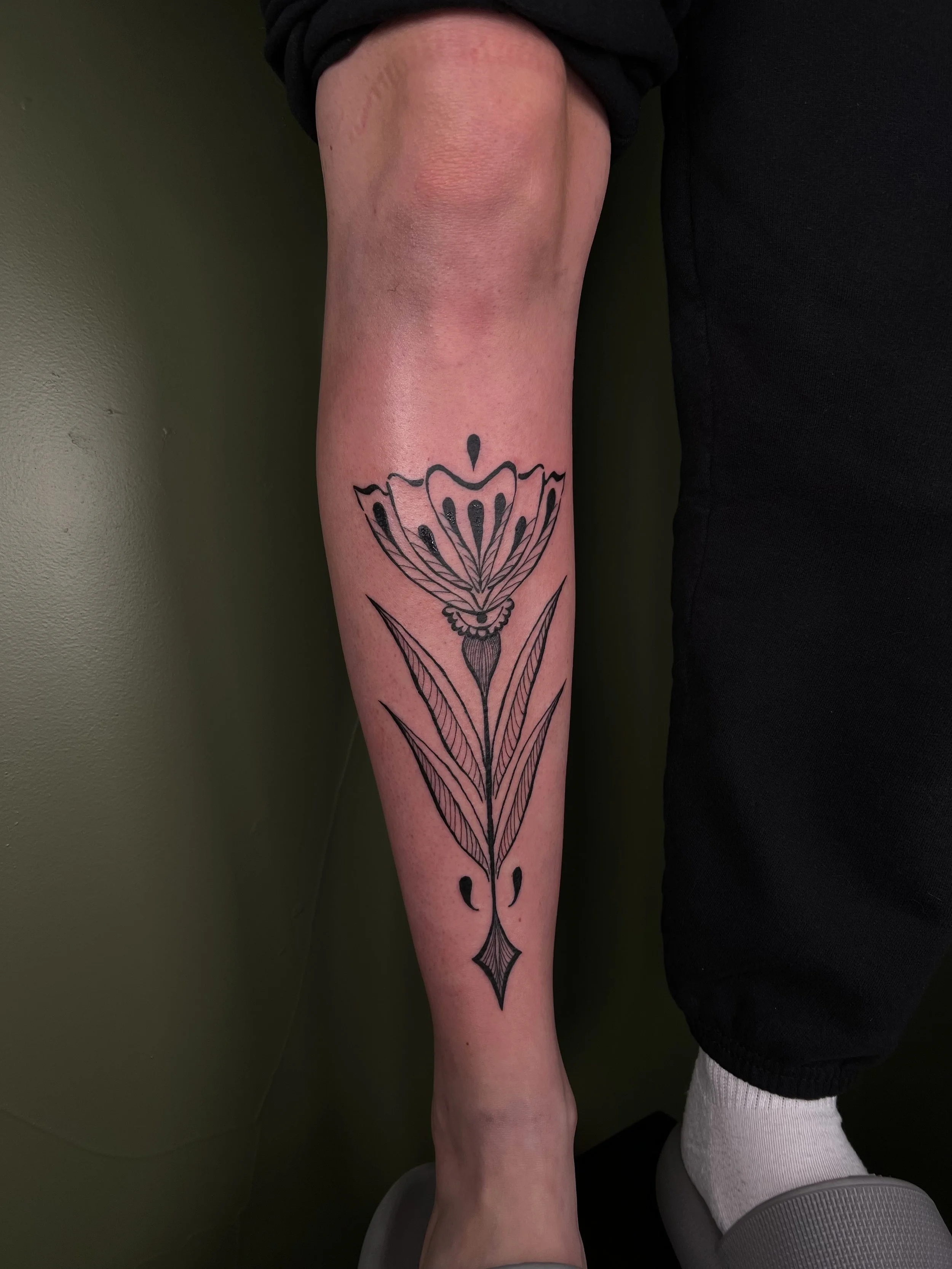 A black ink butterfly tattoo with geometric elements on a person's lower leg.