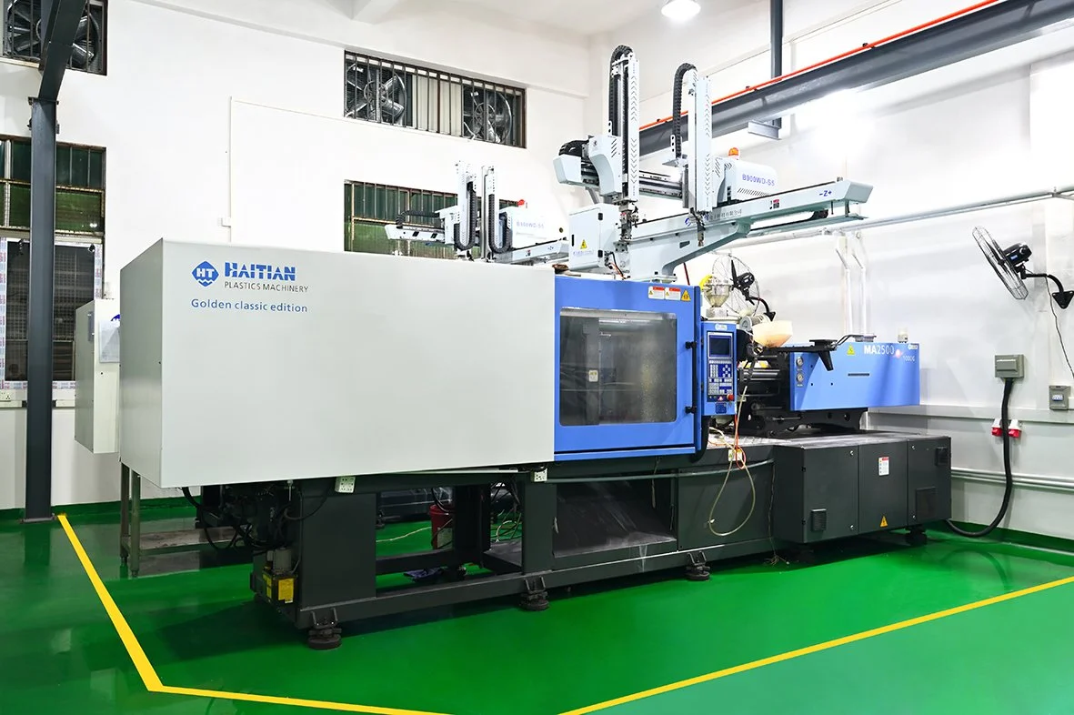 Industrial plastic molding machine in a clean workshop with green floor and white walls.