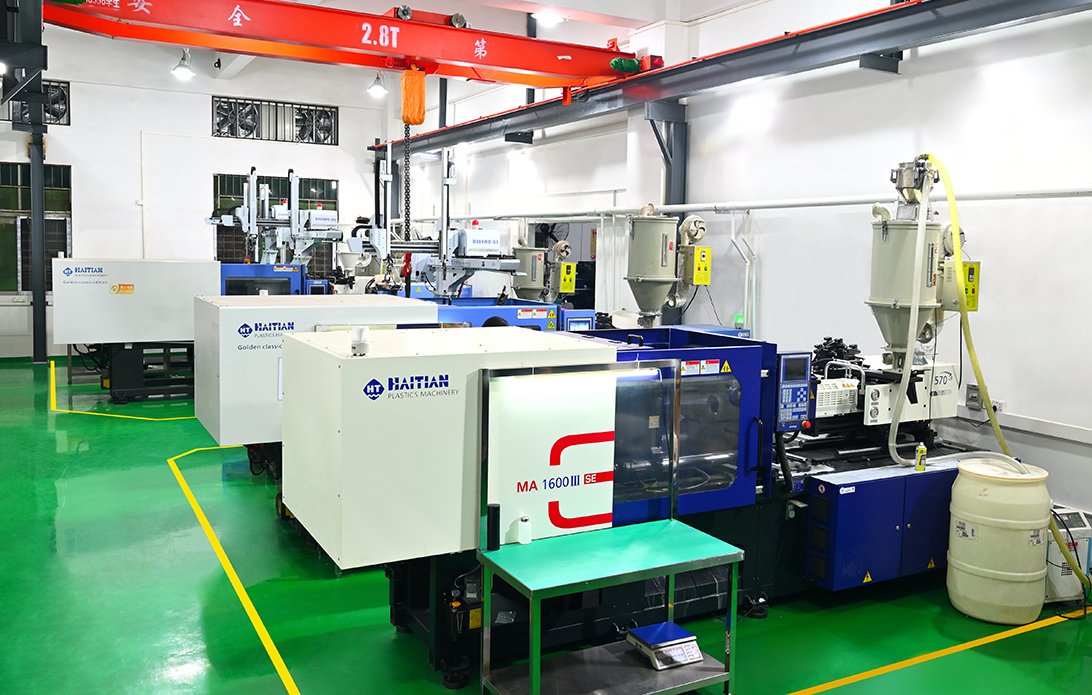 Factory interior with multiple plastic injection molding machines in green zoned workspace.