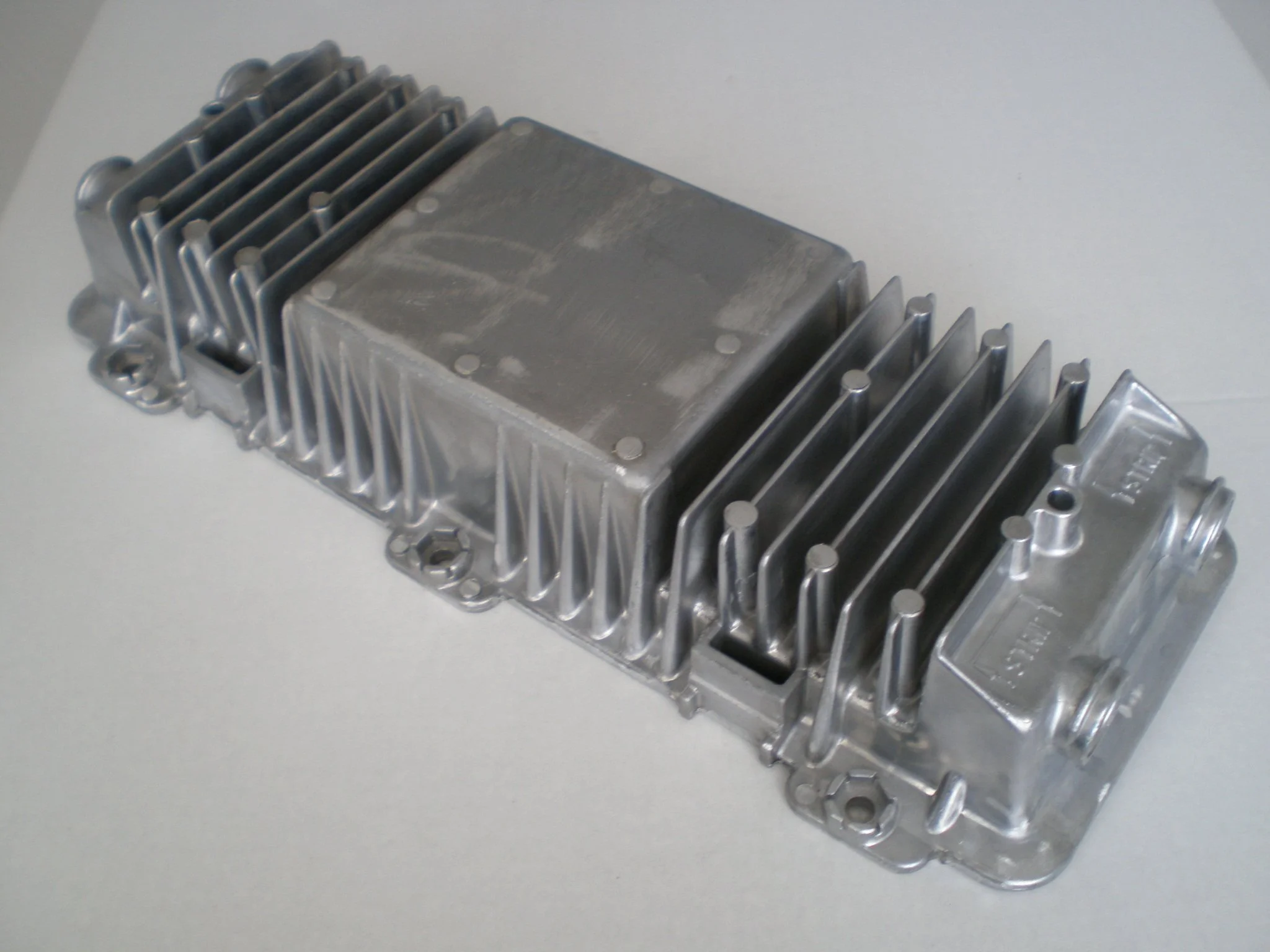 A metallic object resembling a heatsink with fins, placed on a white surface.