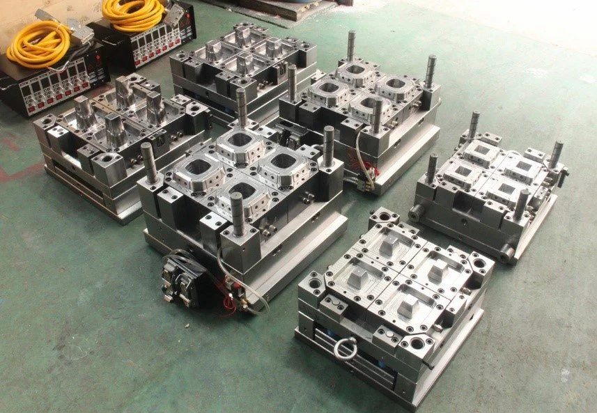Multiple metal molds and industrial equipment placed on a factory floor for manufacturing or molding processes.