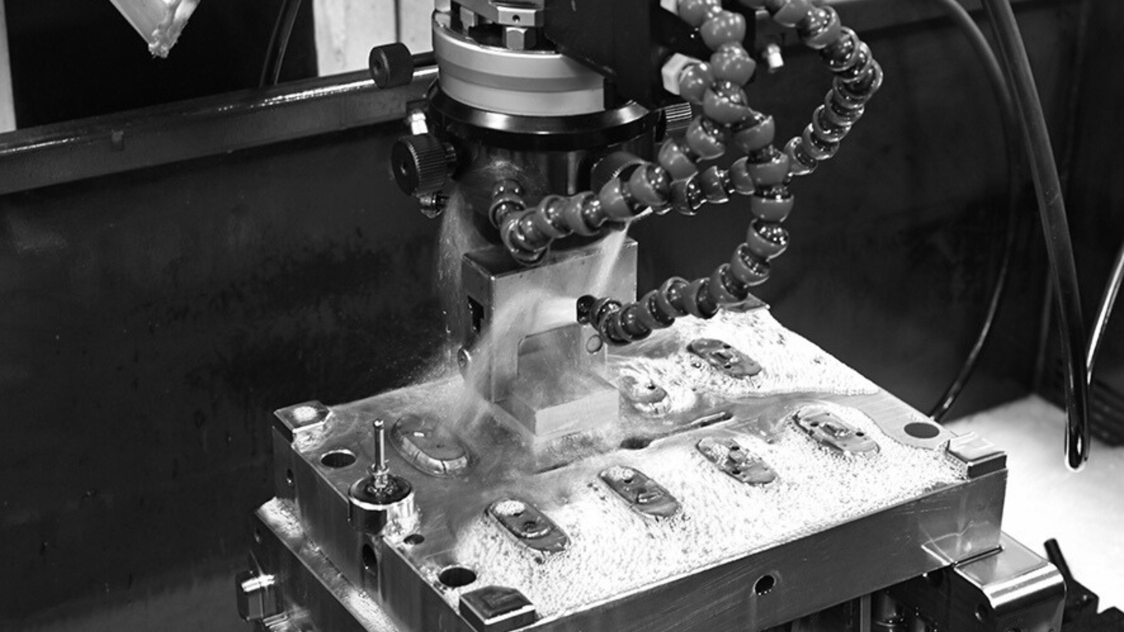 Industrial machine with flexible coolant hose and metal components during manufacturing process.