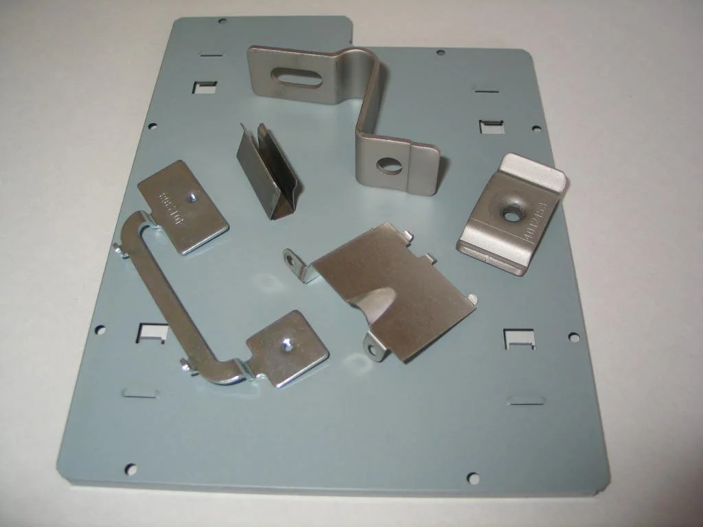 Metal mounting bracket parts laid out on a gray metal plate.