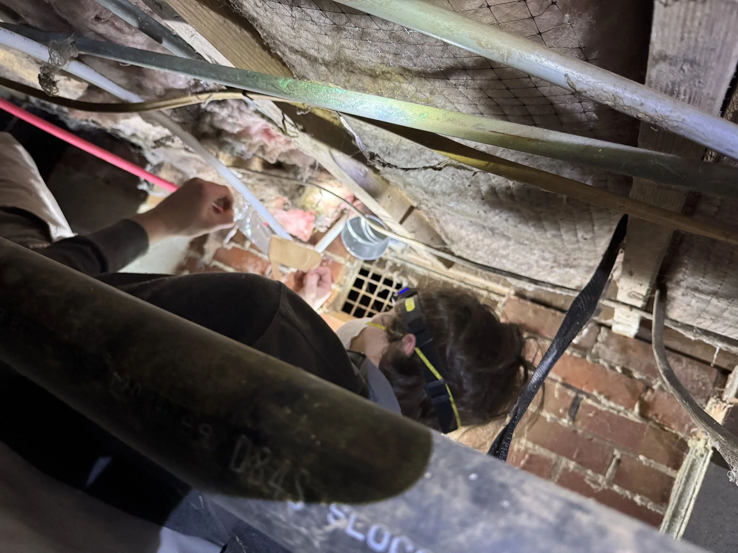 Lint Lift team working in a tight crawlspace to make repairs to a damaged dryer vent. 