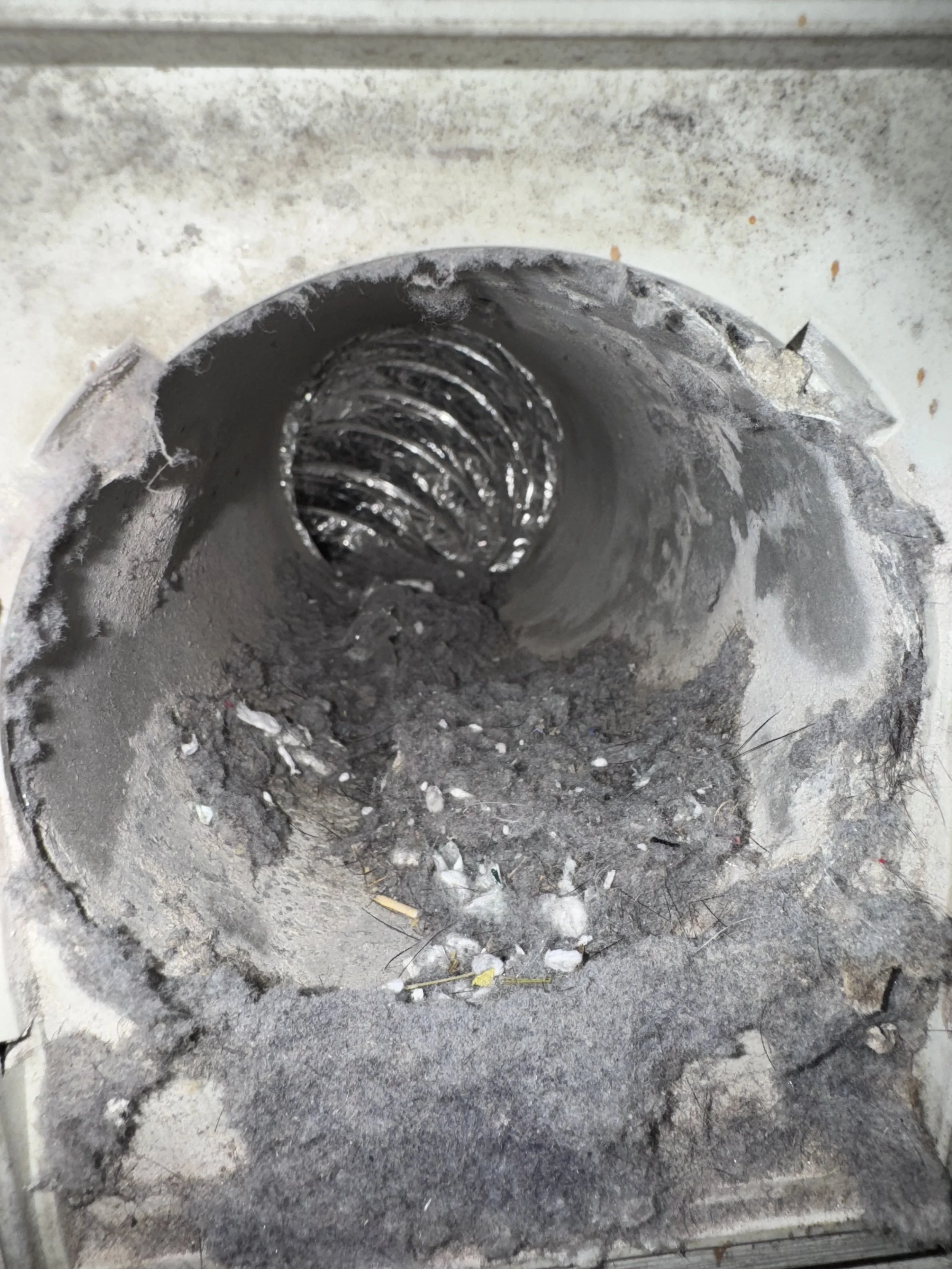 Close-up of a dirty dryer vent with lint build up inside.
