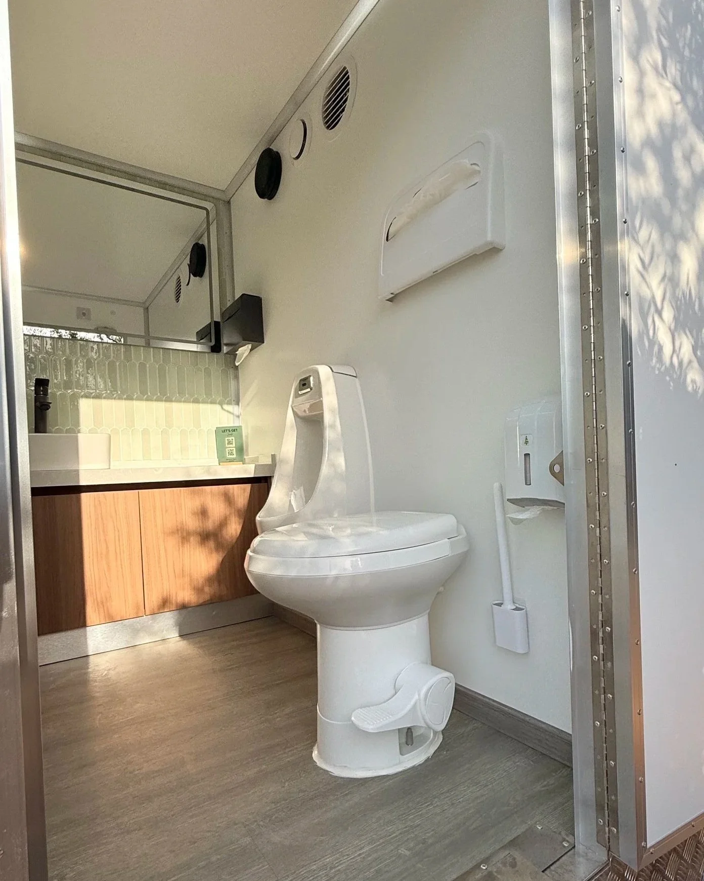 Interior of Olive Collection trailer in the Royal WC fleet with green tile backsplash and white walls and premium fixtures.