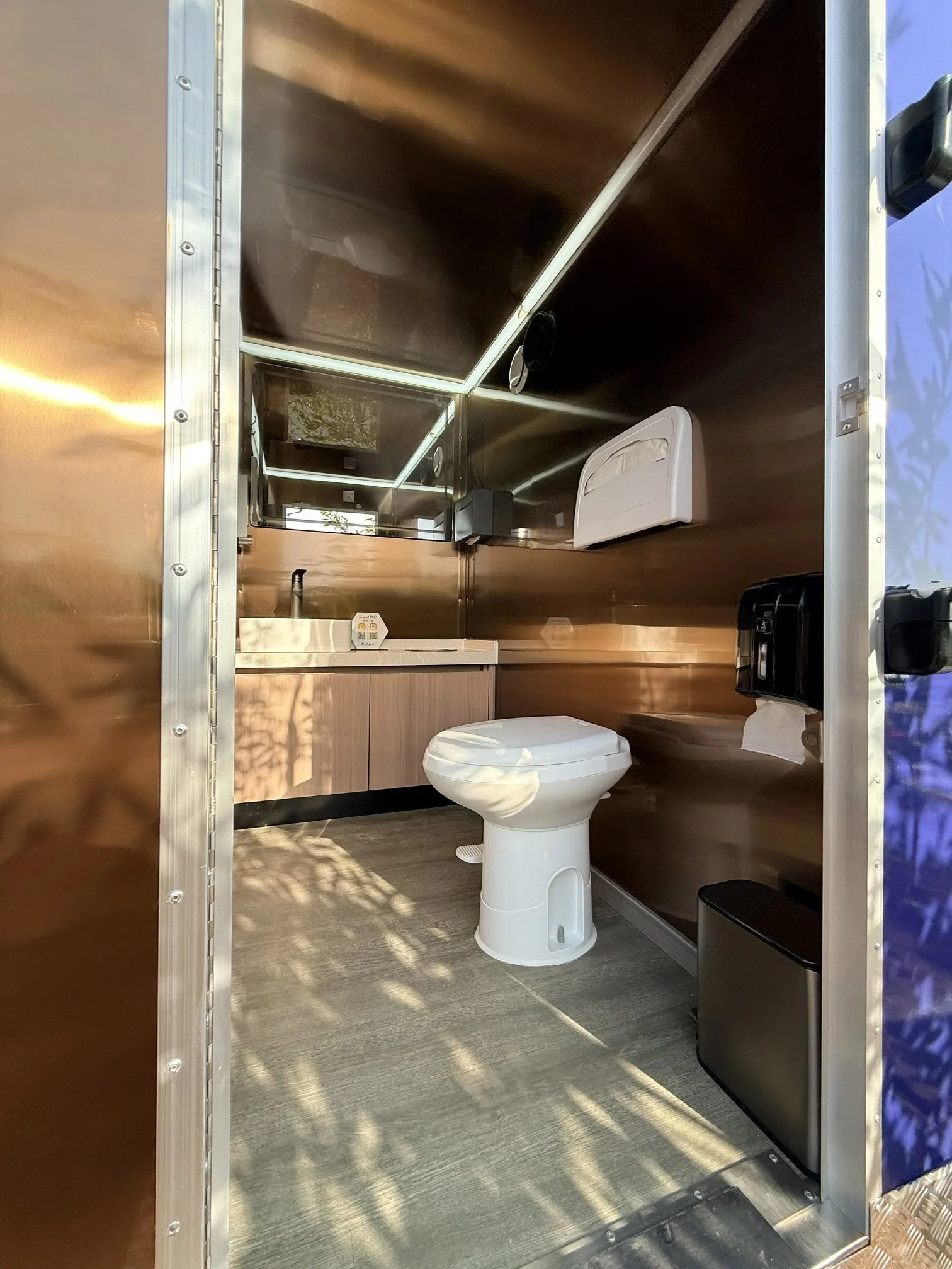 Royal WC interior of the Estate Collection trailer with copper interior panels and premium fixtures.