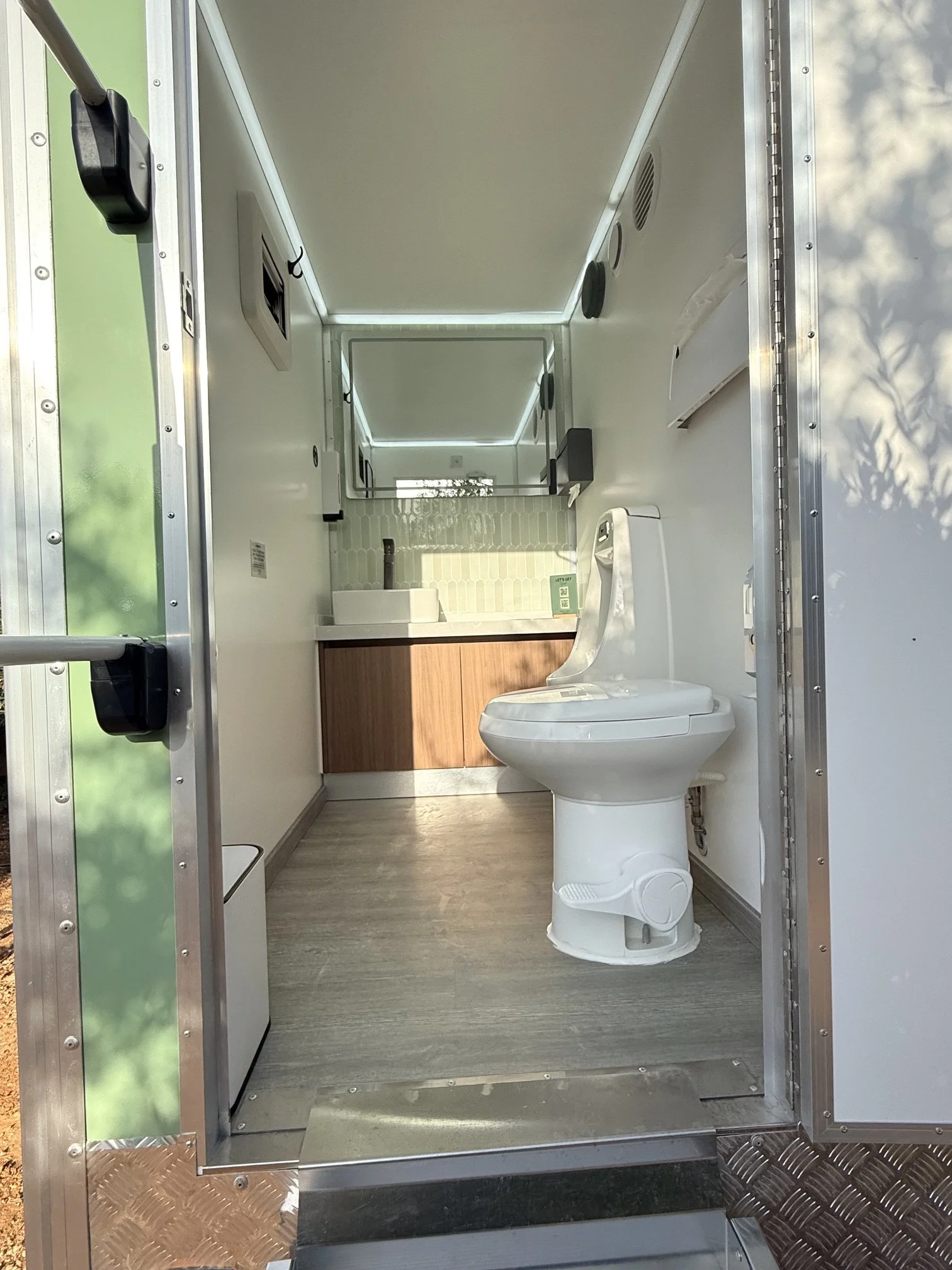 Interior of Olive Collection trailer in the Royal WC fleet at an event in Crete with green tile backsplash and white walls and premium fixtures.