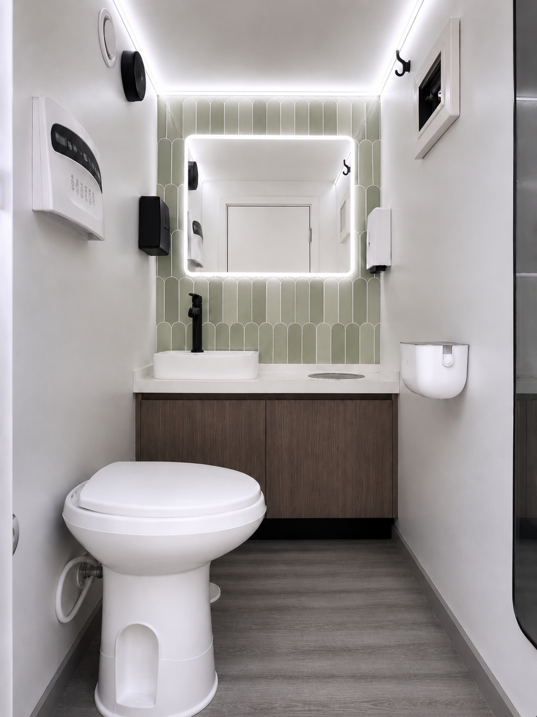 Modern bathroom luxury toilet trailer with vanity, backlit mirror, climate control, green backsplash tile accents.