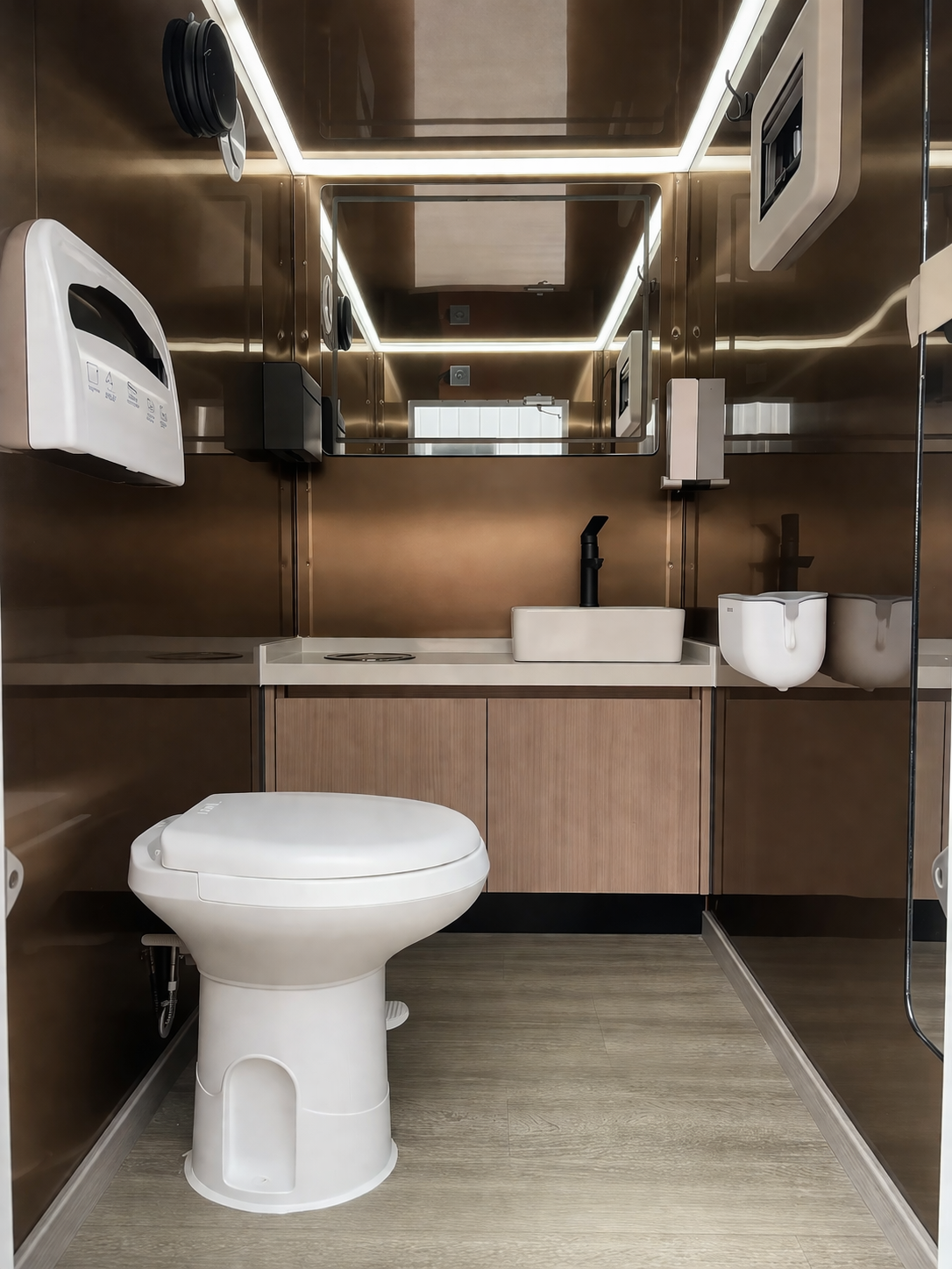 Modern bathroom with wooden cabinetry, white toilet, sink, and mirror, brown walls, and electronic appliances.