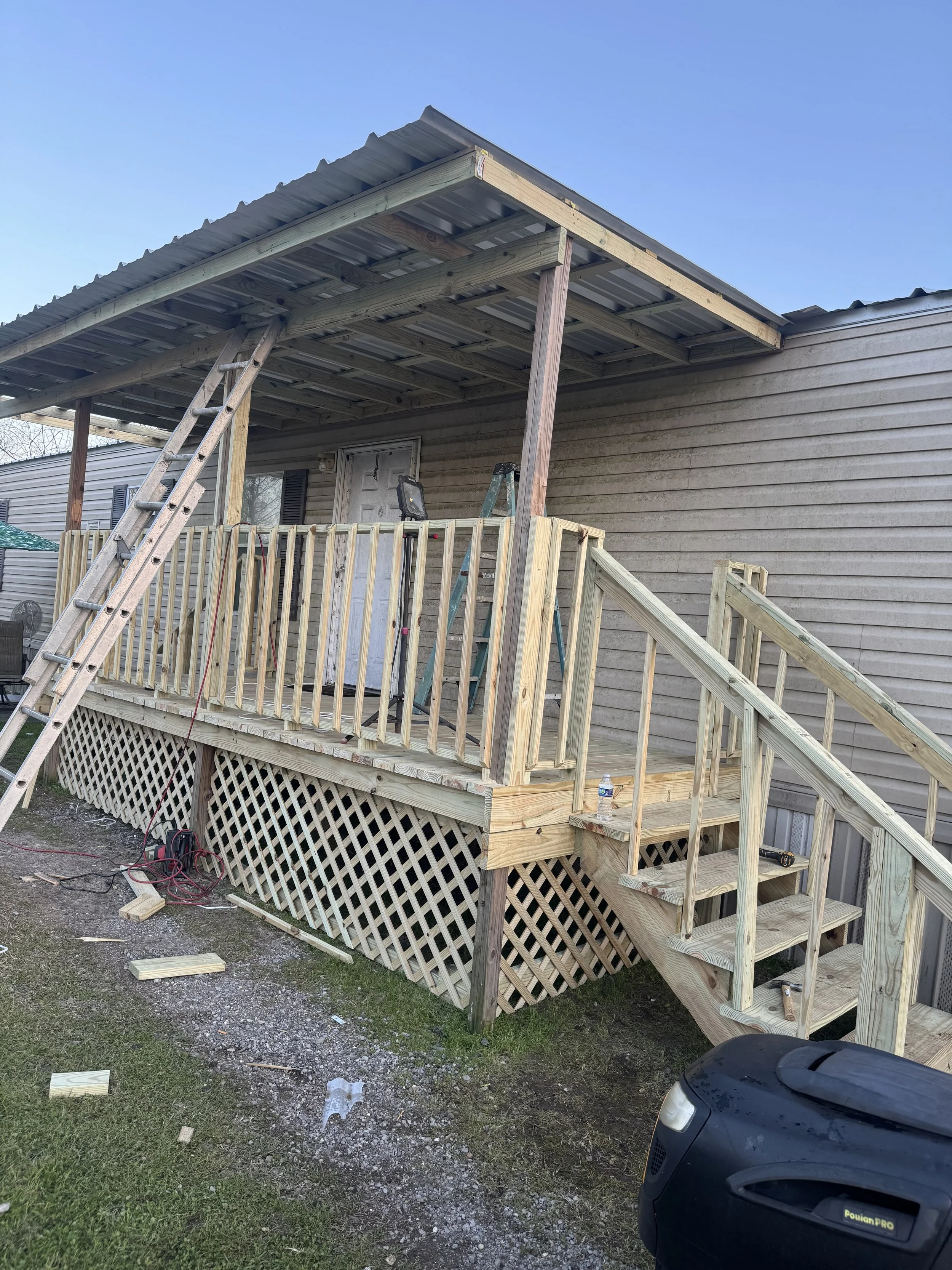 A house exterior with a newly built wooden deck and stairs, scaffolding on top