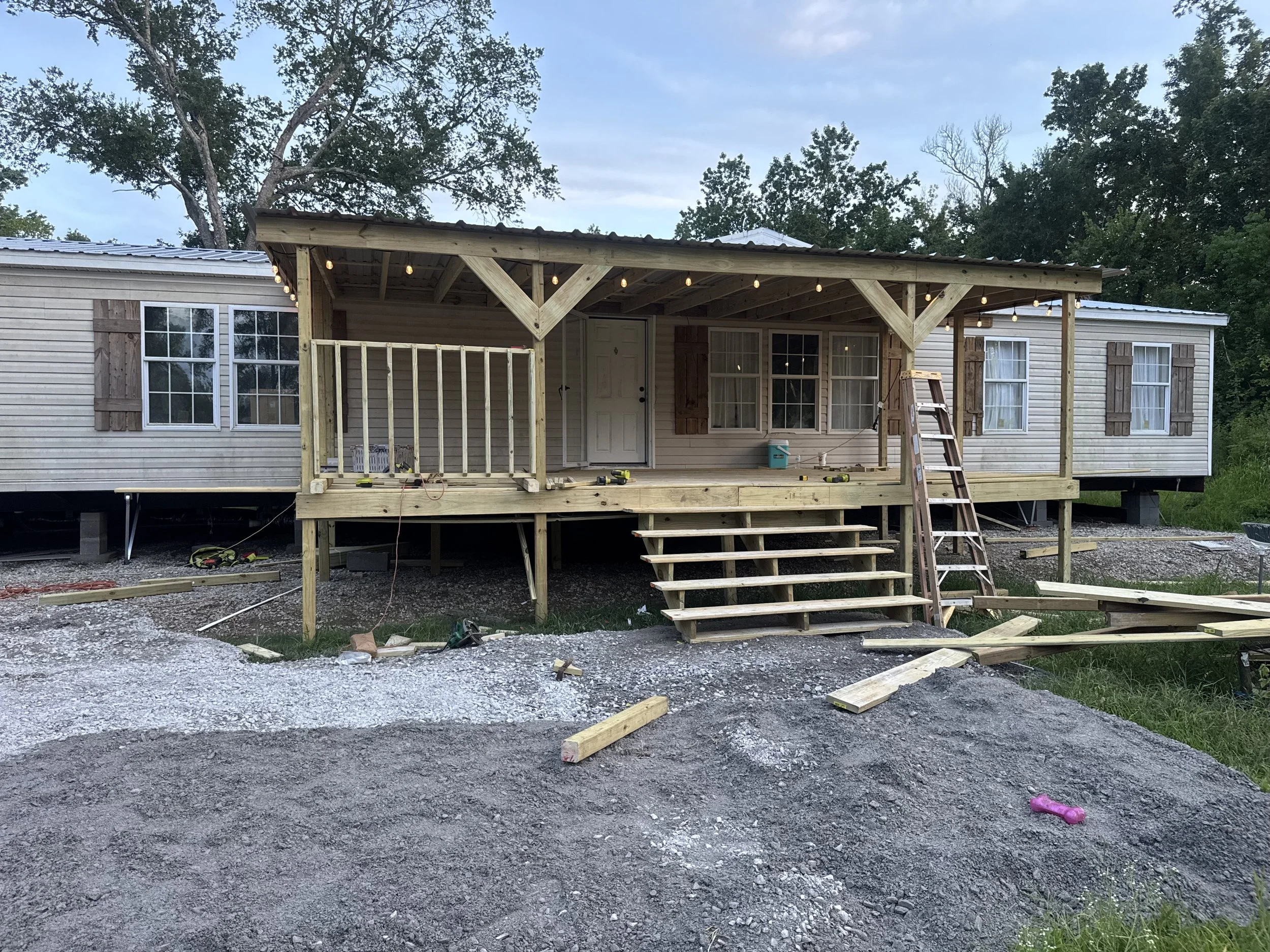 A house with a newly built front porch with steps, surrounded by  string lights hanging from the porch ceiling