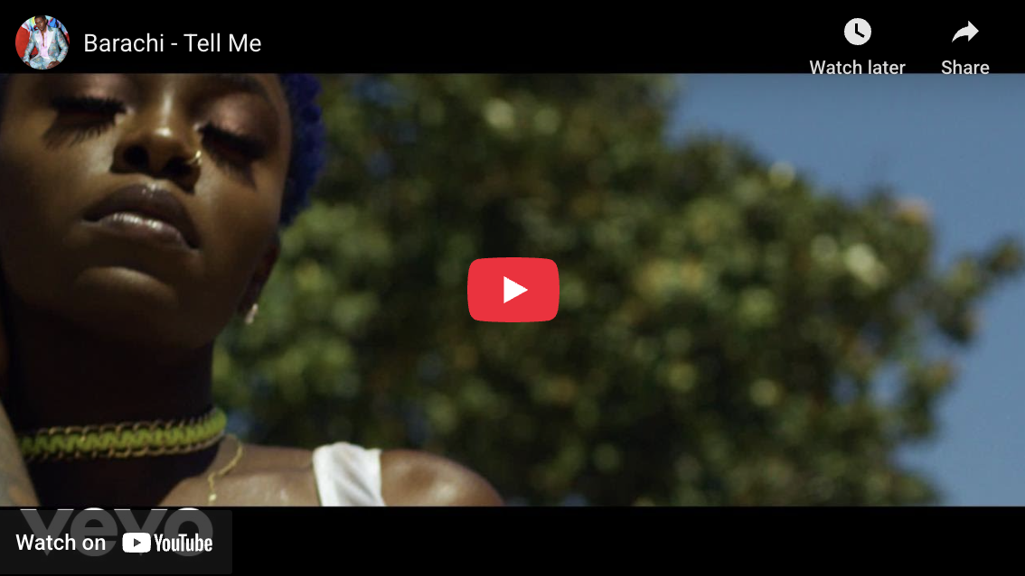 Close-up of a woman's face with closed eyes, wearing a nose ring, a yellow choker, and a white top, outdoors with trees and blue sky in the background.