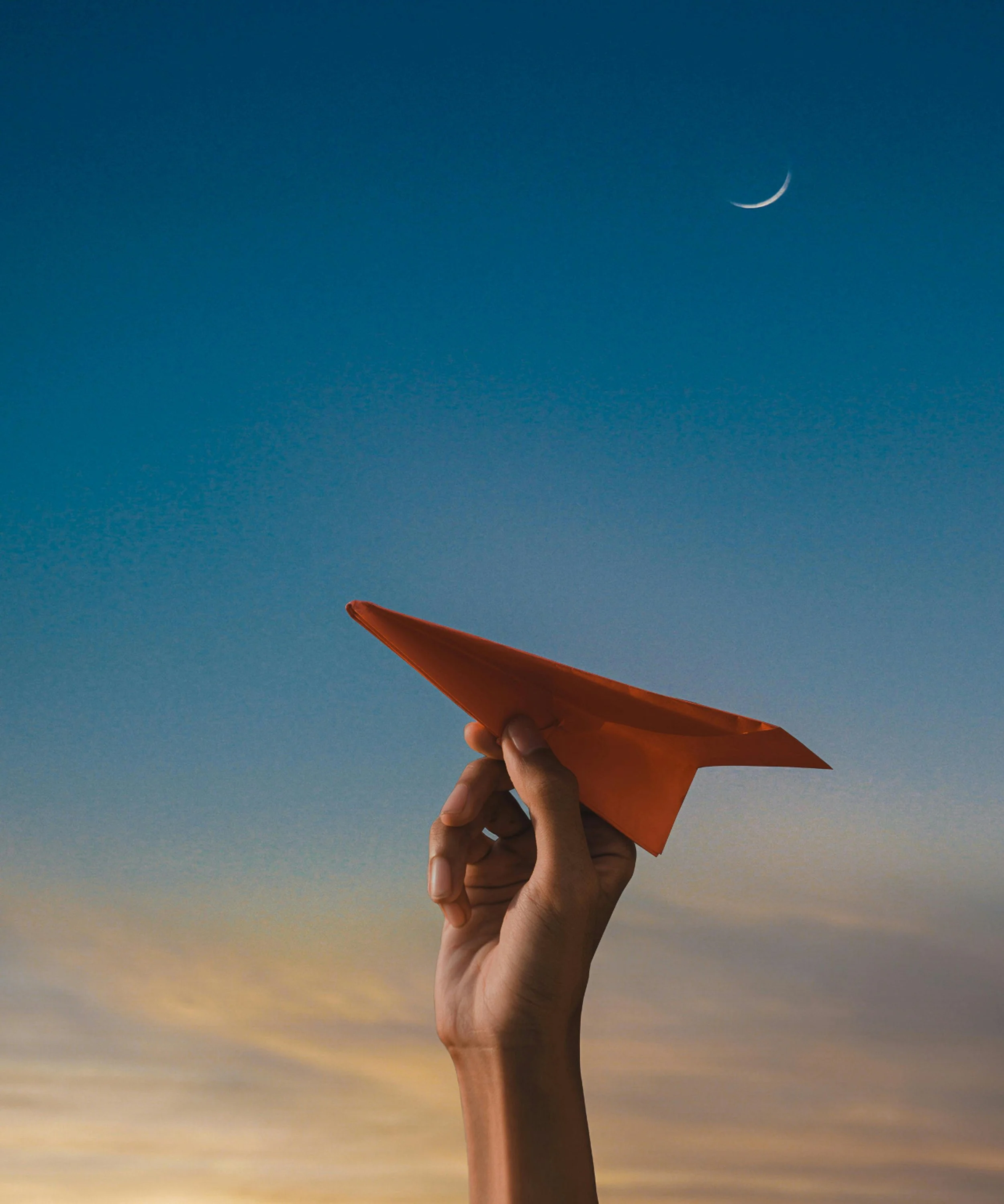 Avion en papier tenu dans la main avec un ciel bleu à l'arrière-plan