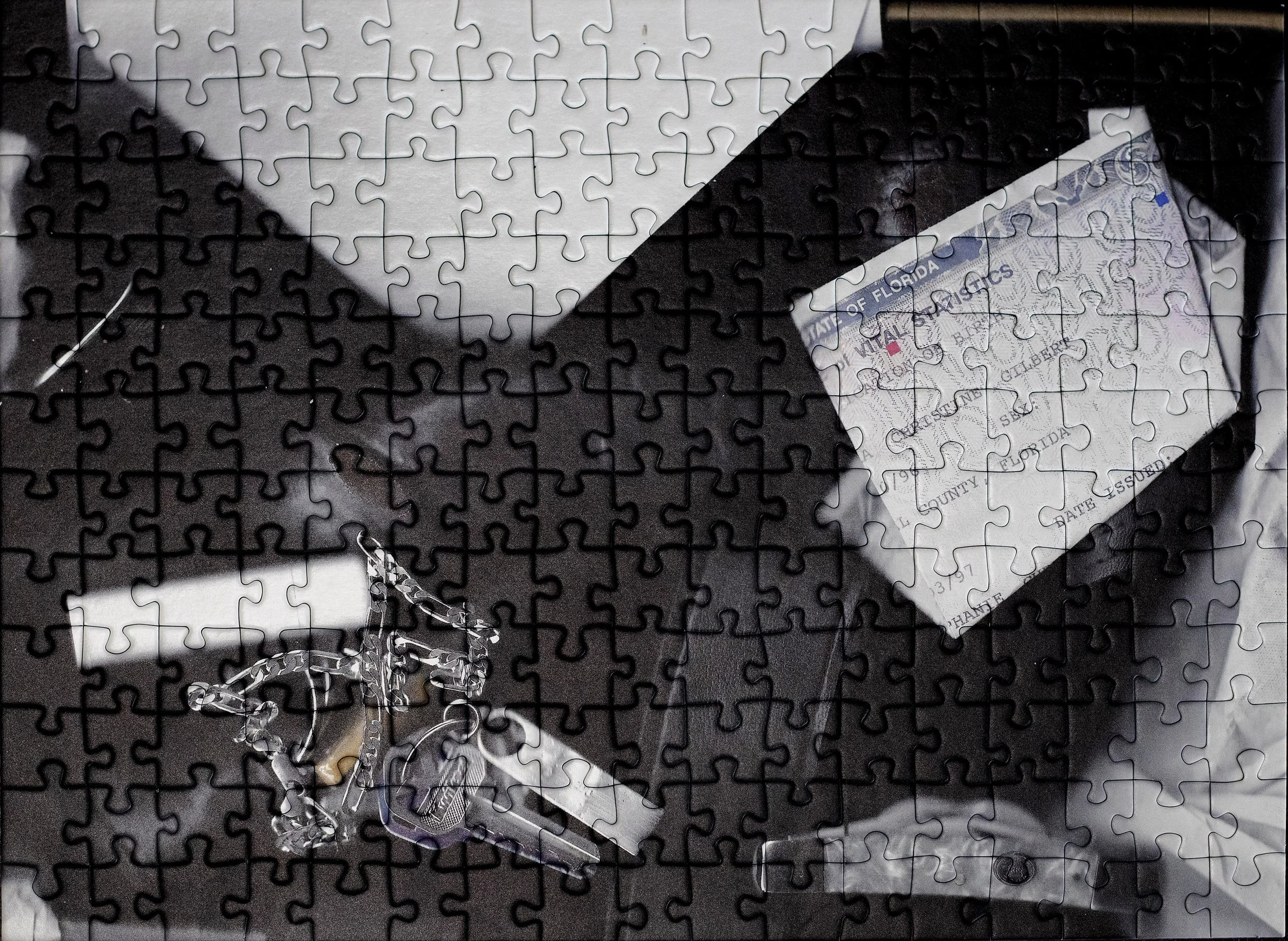A completed jigsaw puzzle depicting a collection of personal items, including a dildo, a chain, a knife, and some chapstick.
