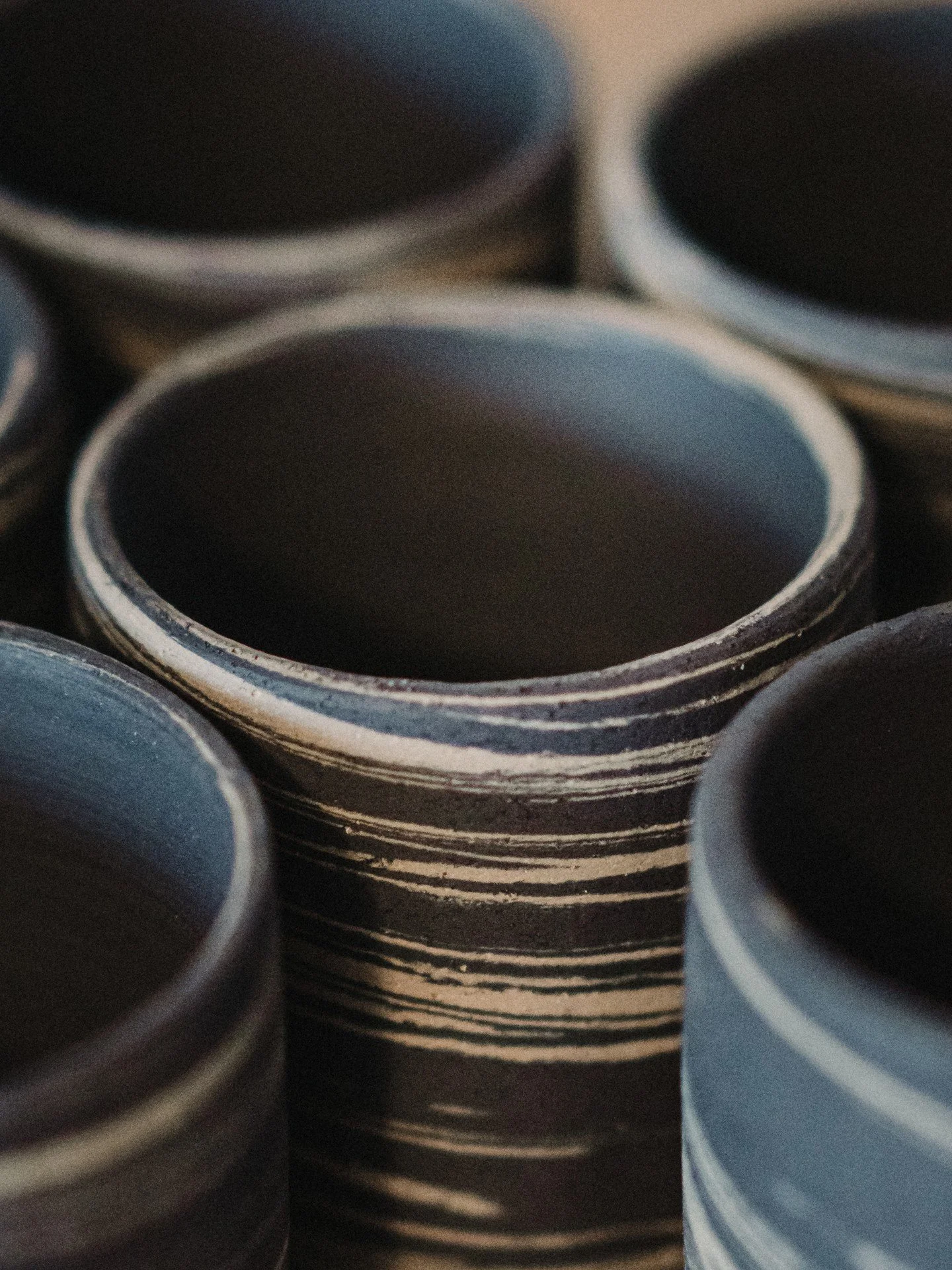 I've been revisiting some of my very first cup designs, this time with a straighter shape.

I threw and trimmed them mostly by feel, without much measuring, which made for a set of cups that are similar but never quite identical.

There's something a