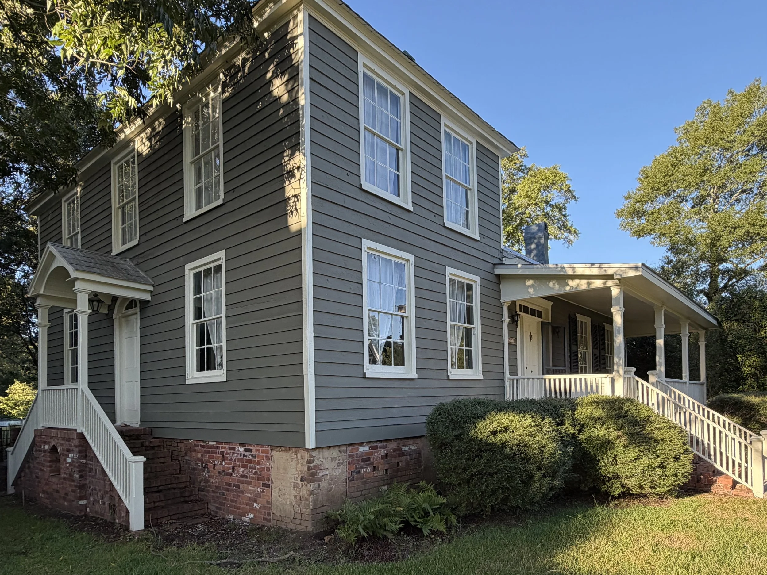 Historic home at 212 Water Street in Washington, Georgia, with gray clapboard siding, tall windows, and a covered porch.