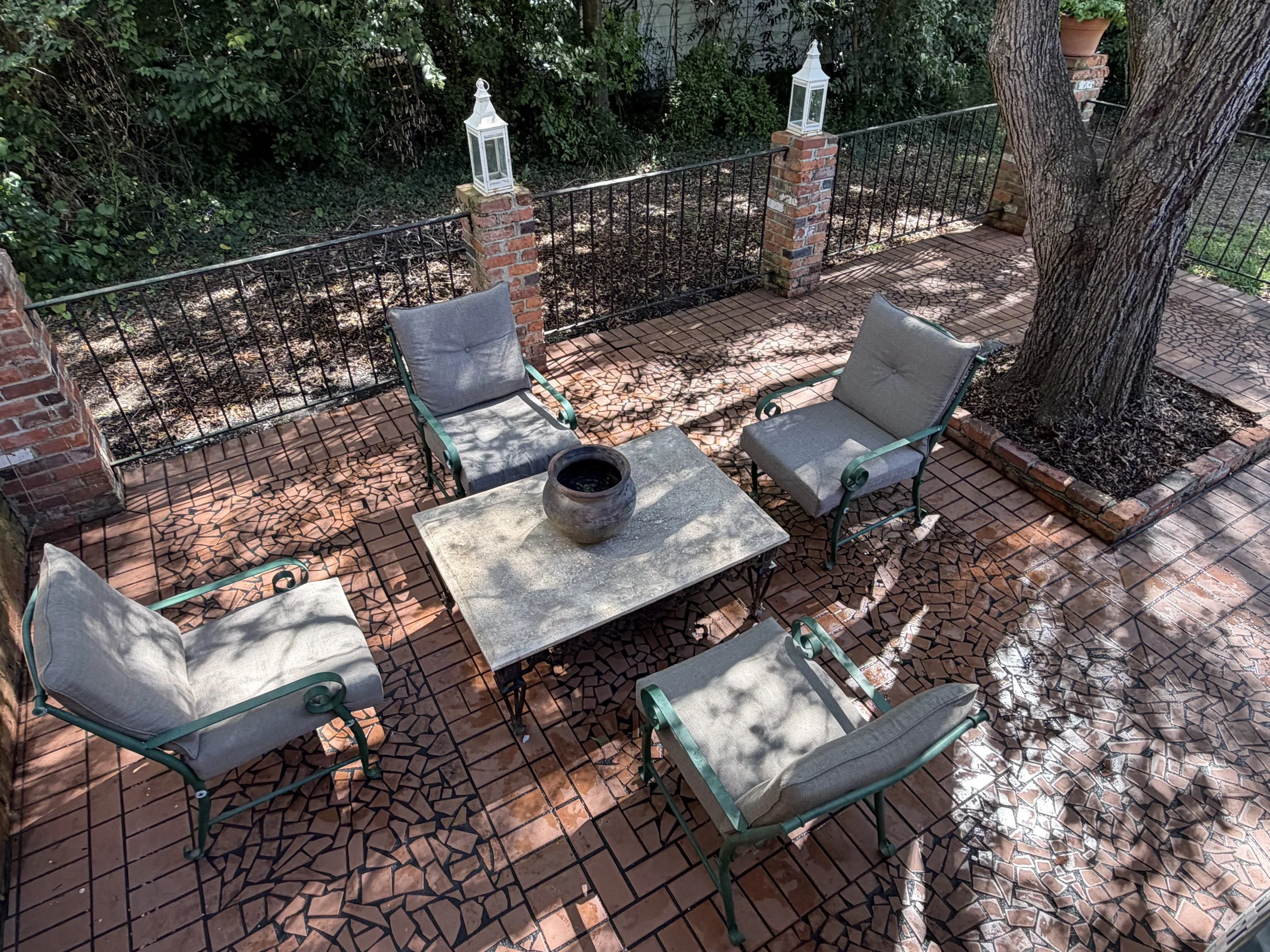 Overhead view of courtyard seating and patterned brick paving surrounding a mature tree.