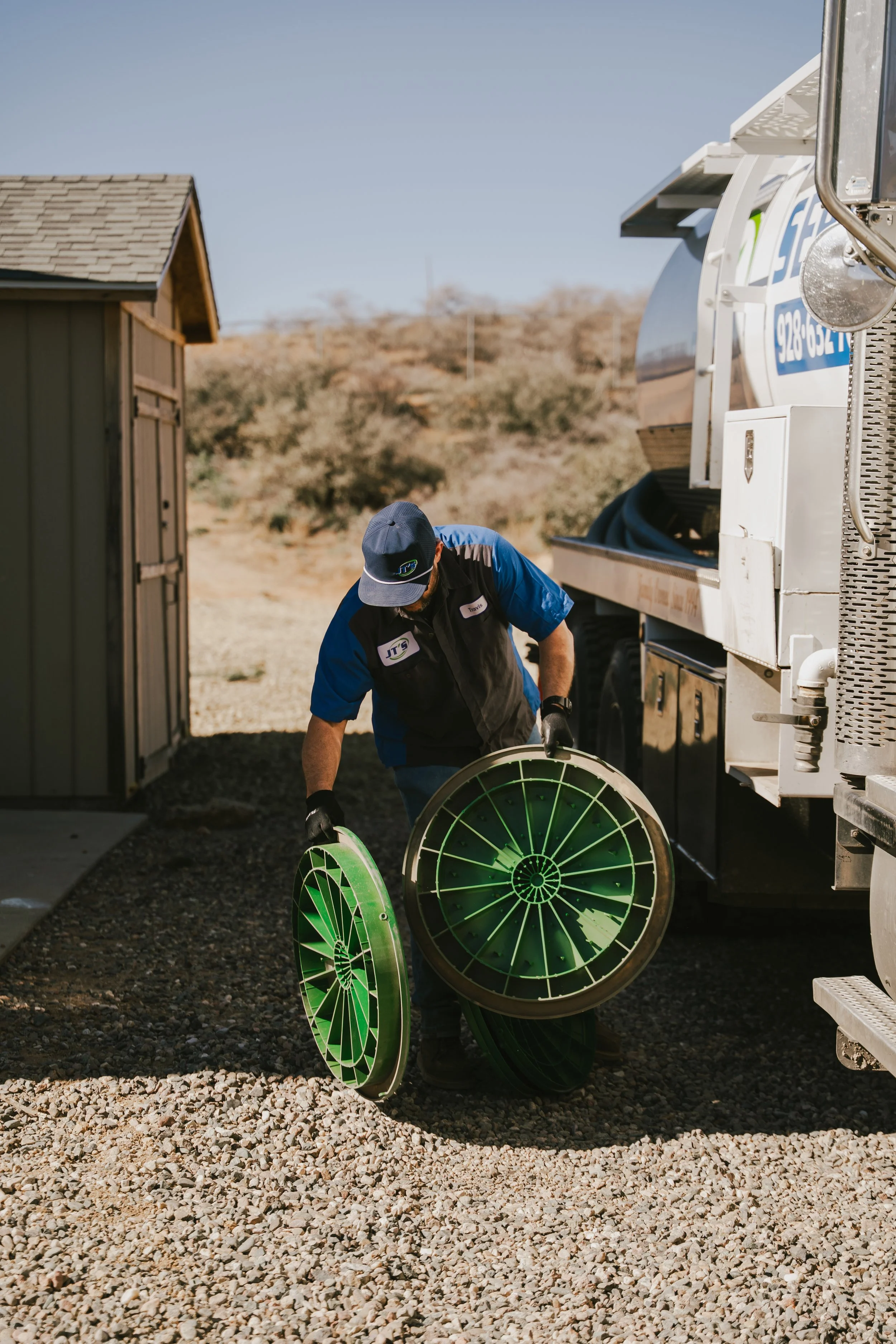 JT's Septic employee holding green septic tank lids inspecting them before replacing them on a septic tank.