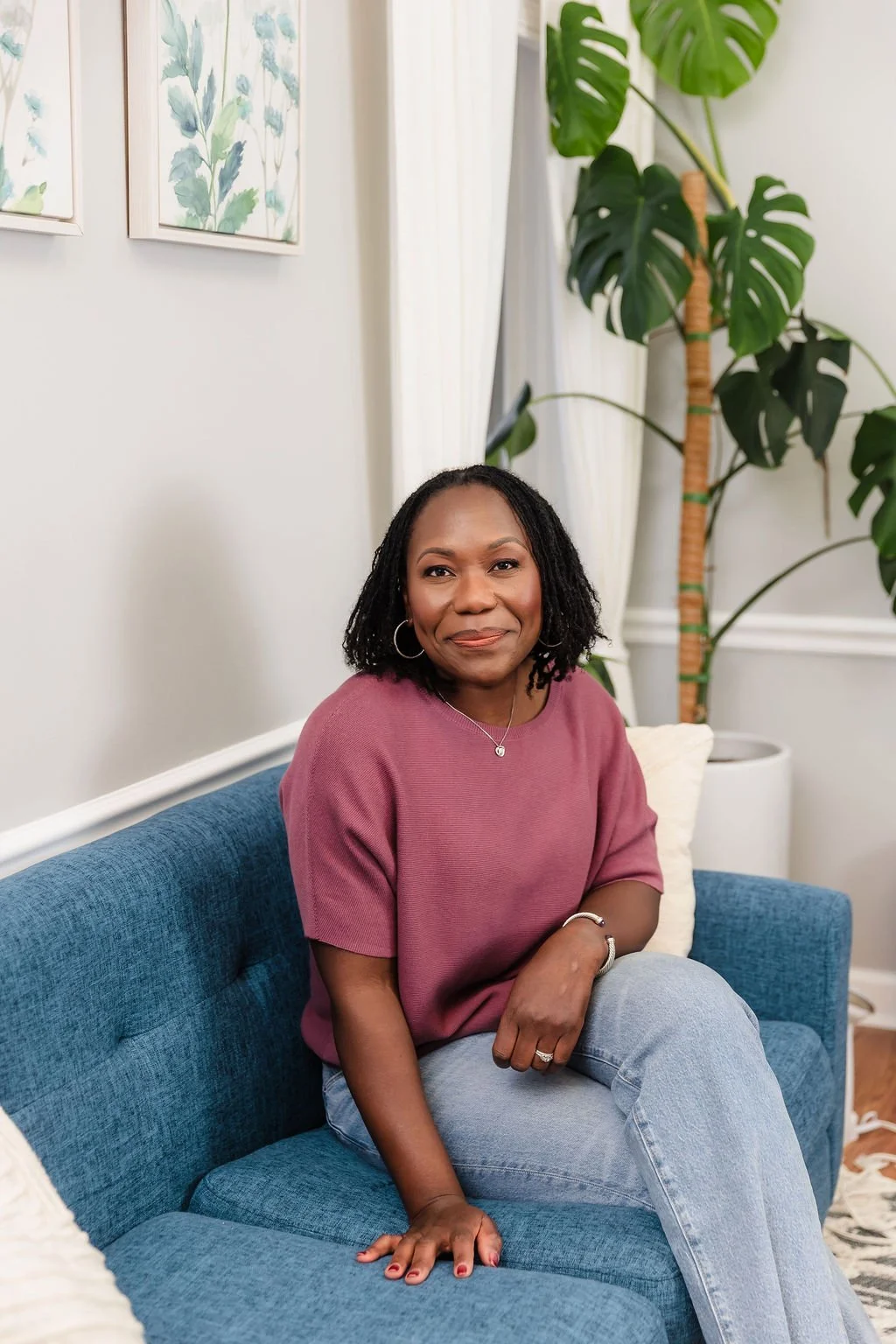 A woman with pink shirt and jeans smiling
