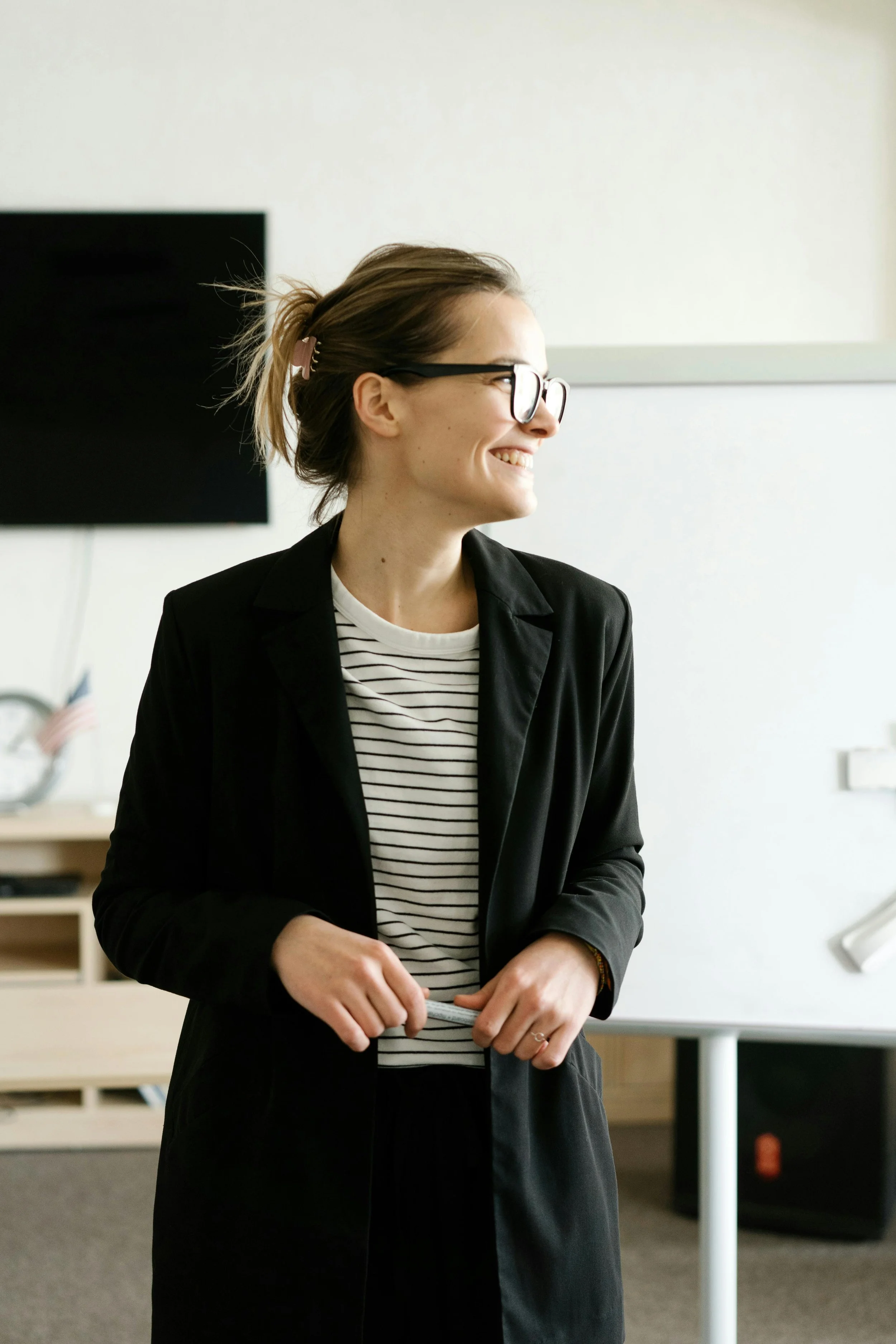 A woman with a black coat, striped shirt, and glasses