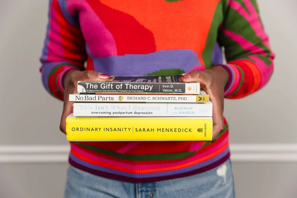Woman with striped shirt holding books on therapy