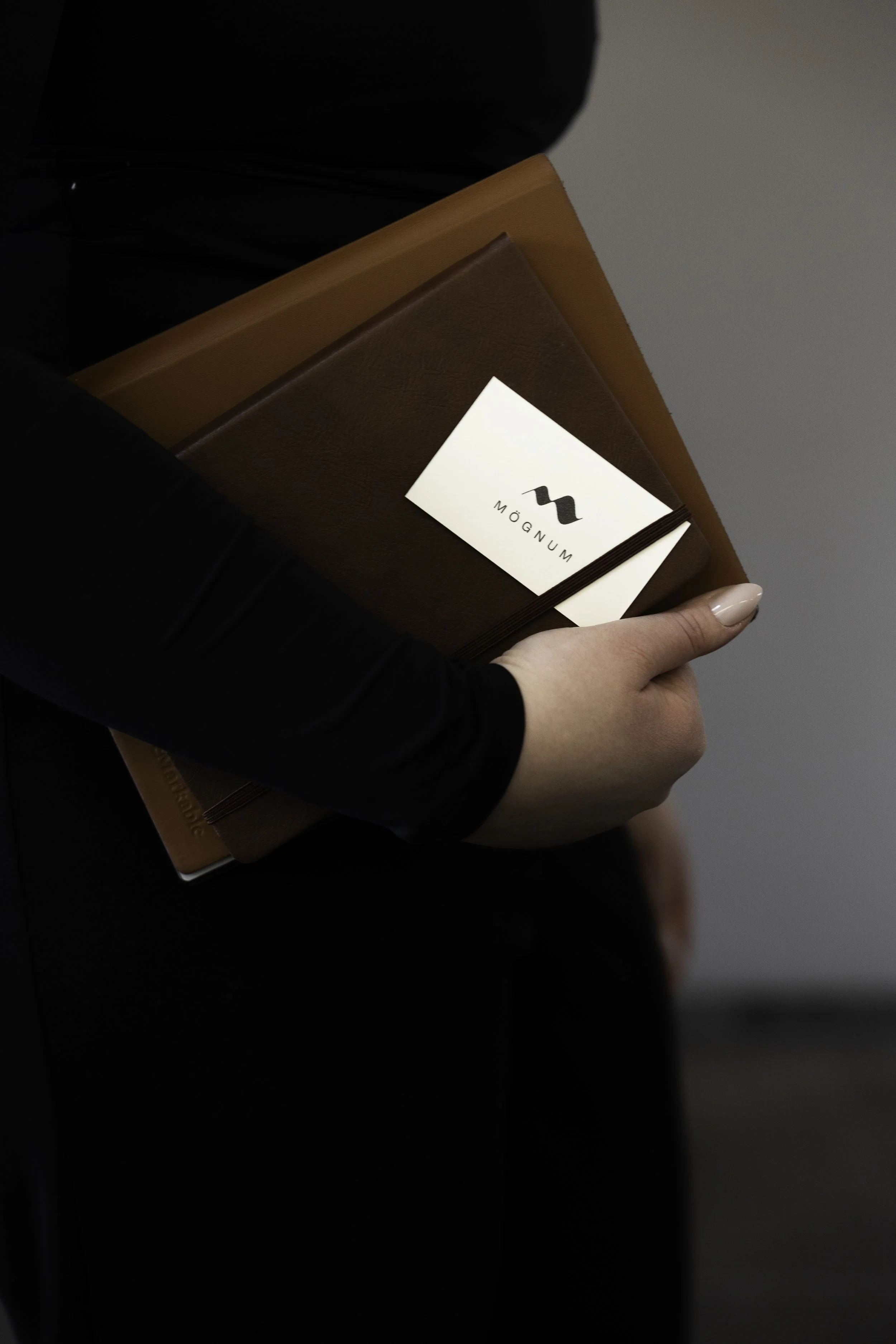 Mynd af minnisbókum í hendi og nafnspjaldi með logó Mögnum