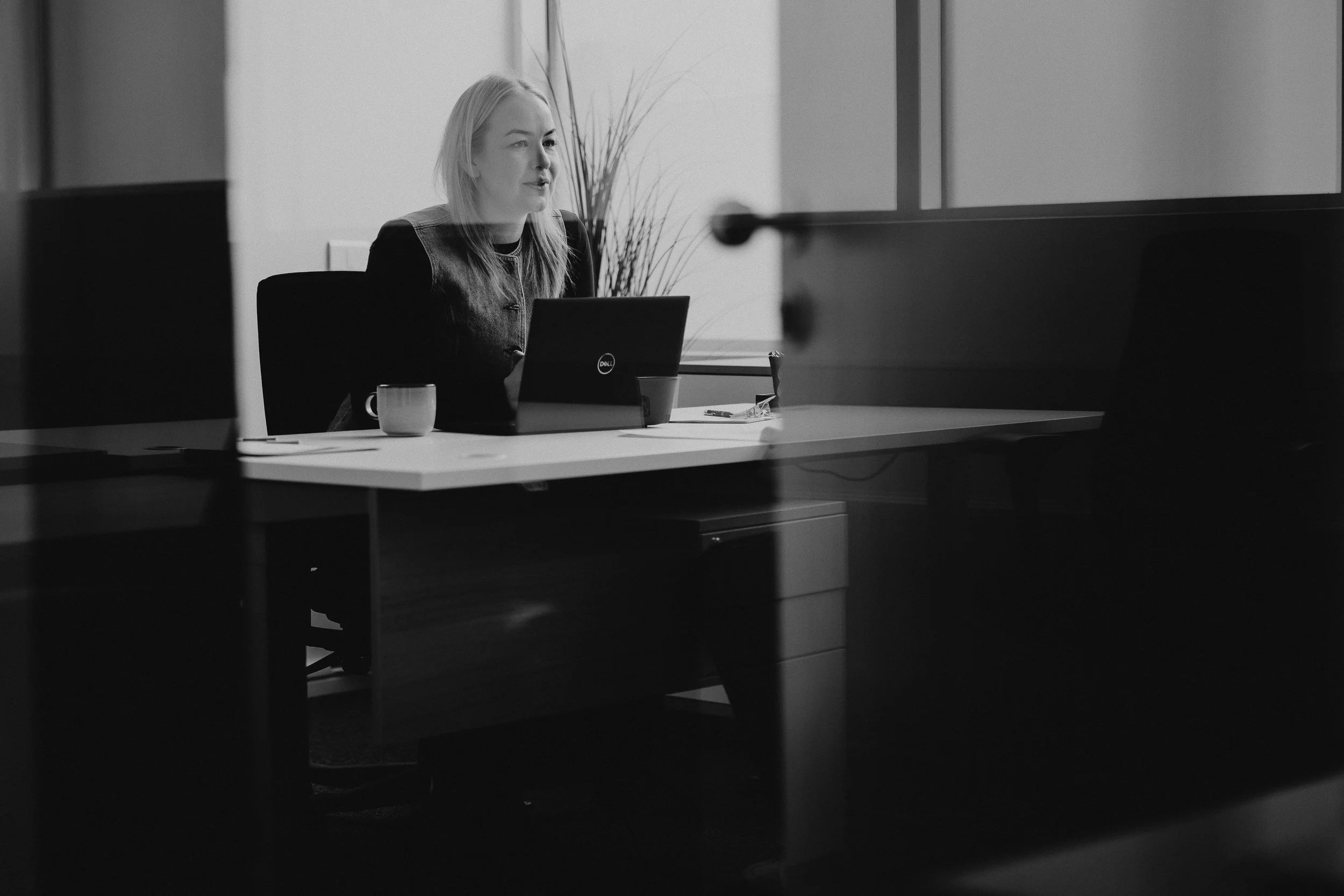 Thelma situr við skrifborðið sitt og vinnur í tölvu