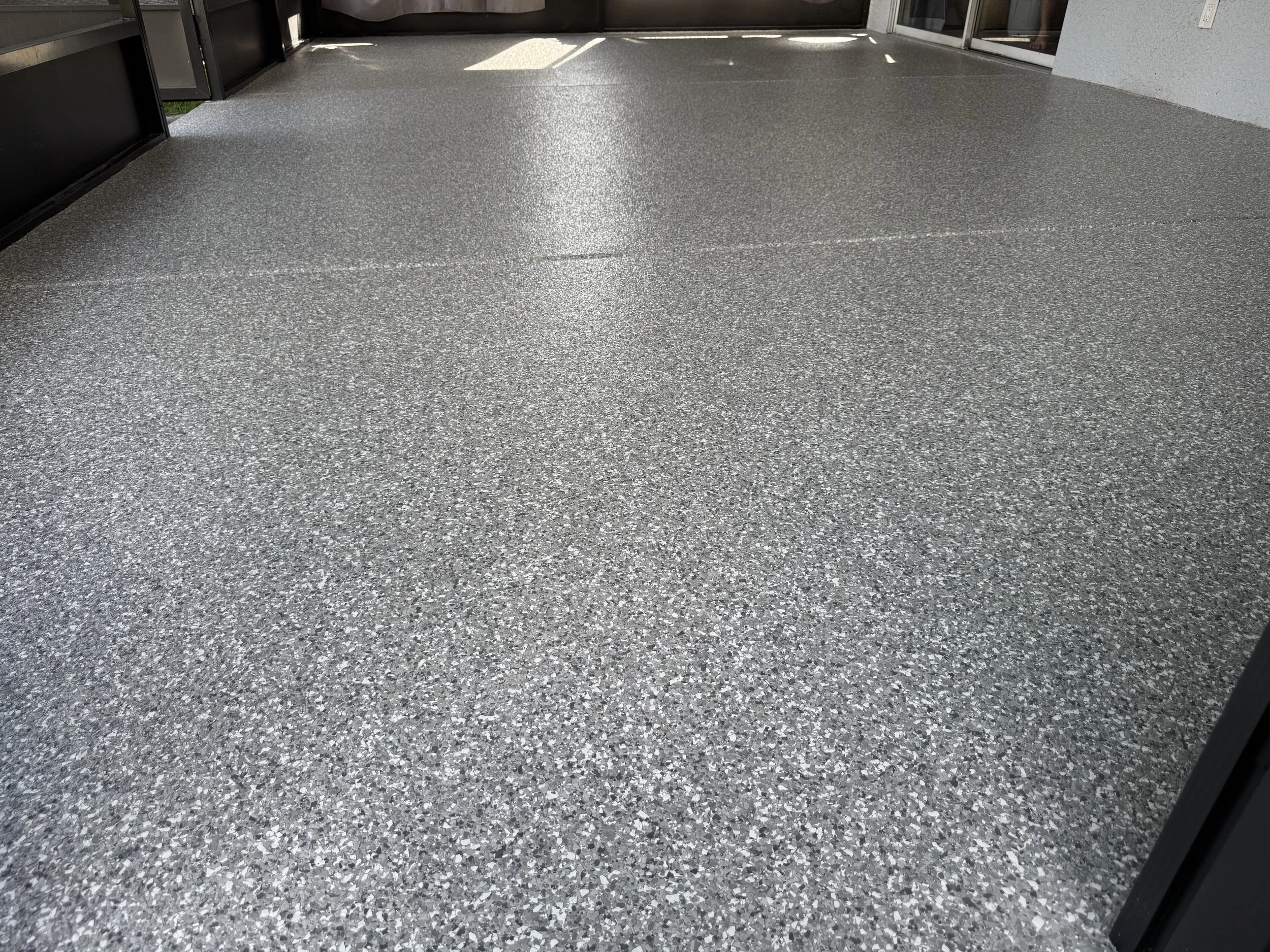 A clean, speckled gray polyaspartic patio floor, epoxy, tampa area