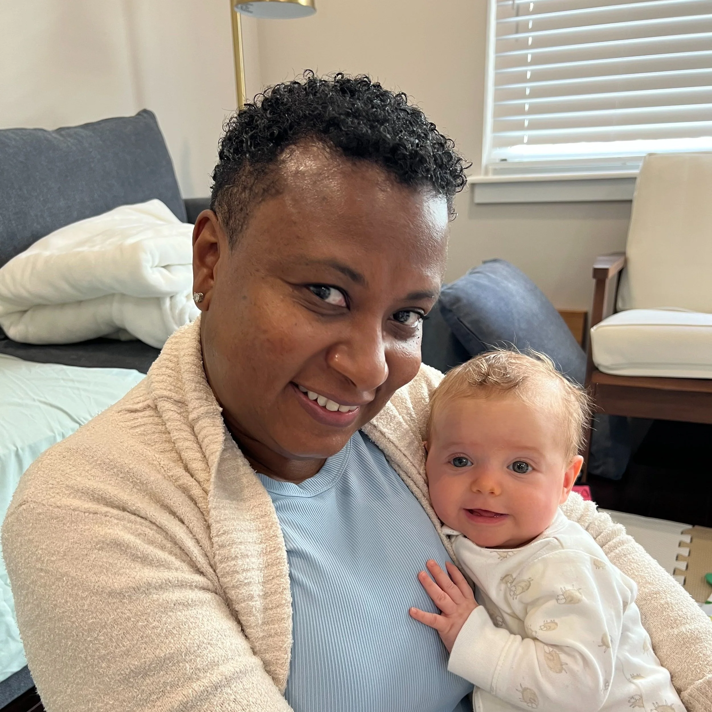 Ria Savoy, postpartum doula and sleep consultant holding a smiling baby at Philadelphia home.