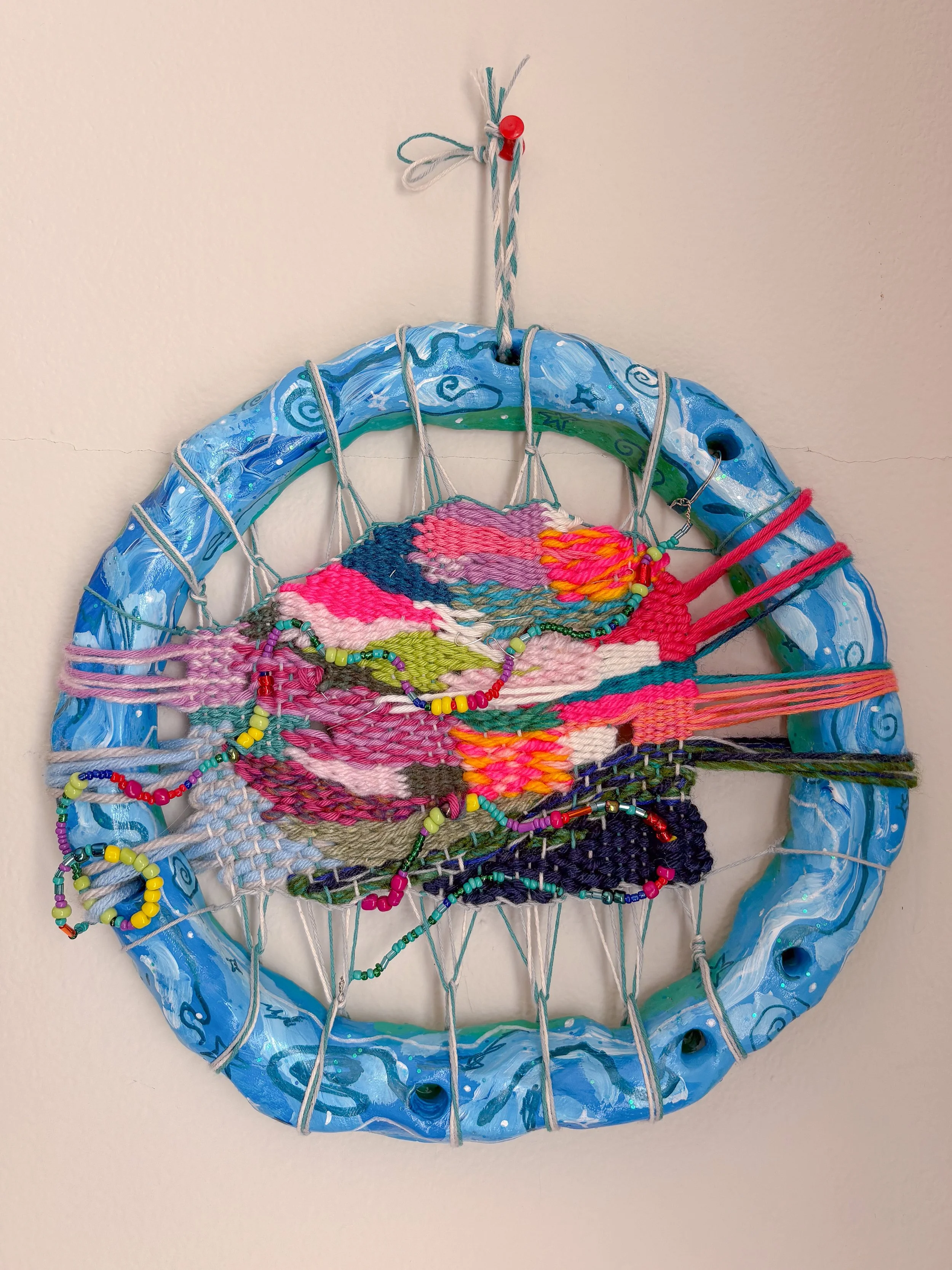 "A 90s Pacific Northwest teen angst-filled bedroom, poster-covered walls, finding yourself in music." --- Celestial (2026). 9" x 9" x 1". Thread, yarn, clay, wire, beads, acrylic paint, ribbon, glitter, and glue. SOLD. 