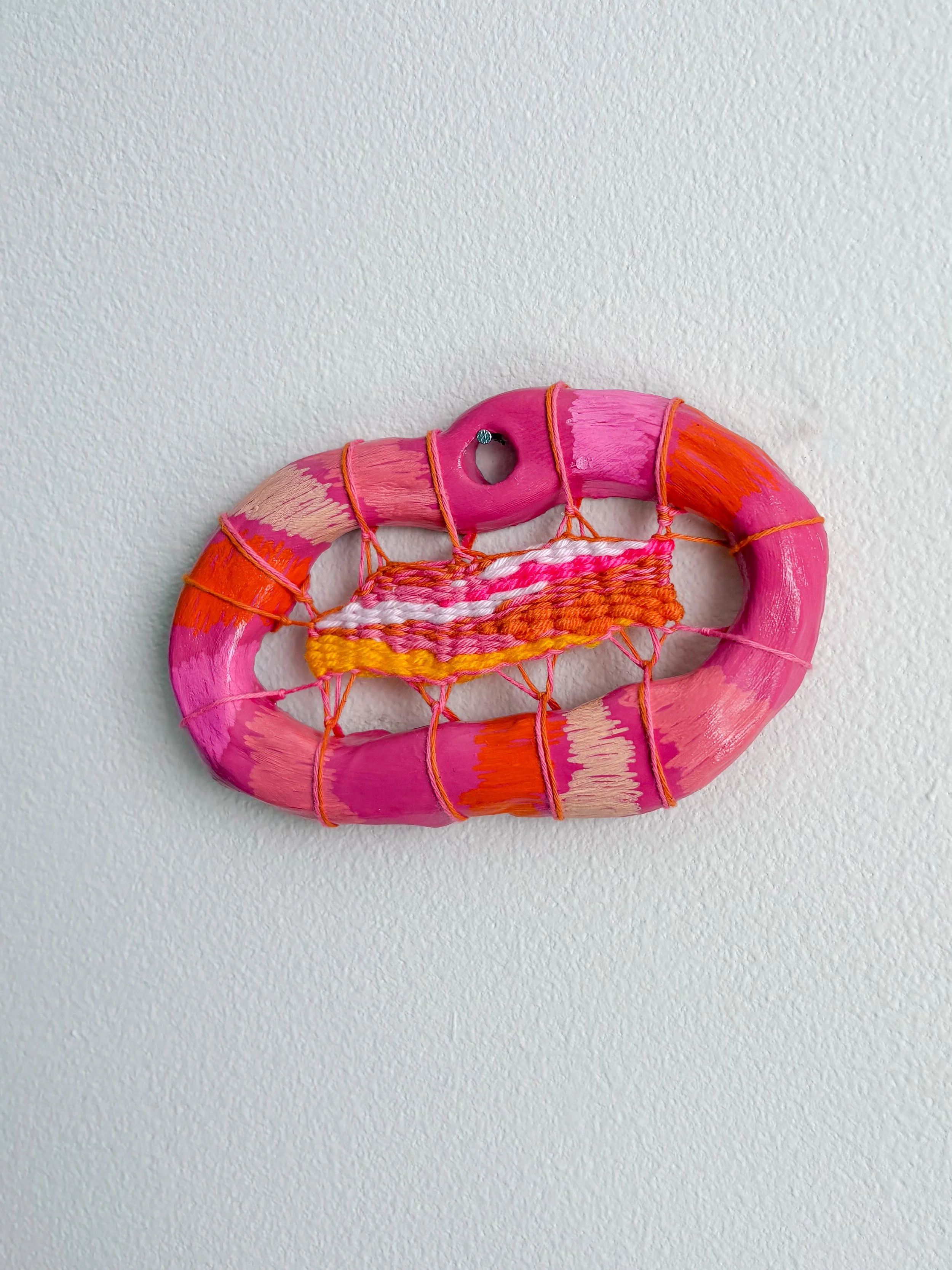 "Rainbow sherbet in a cup after a sunny day in the park. Childhood orange and pink plaid wallpaper." --- Orange and Pink (2025). 3.5" x 6" x .75". Thread, yarn, clay, acrylic paint, and glue. Available in shop.