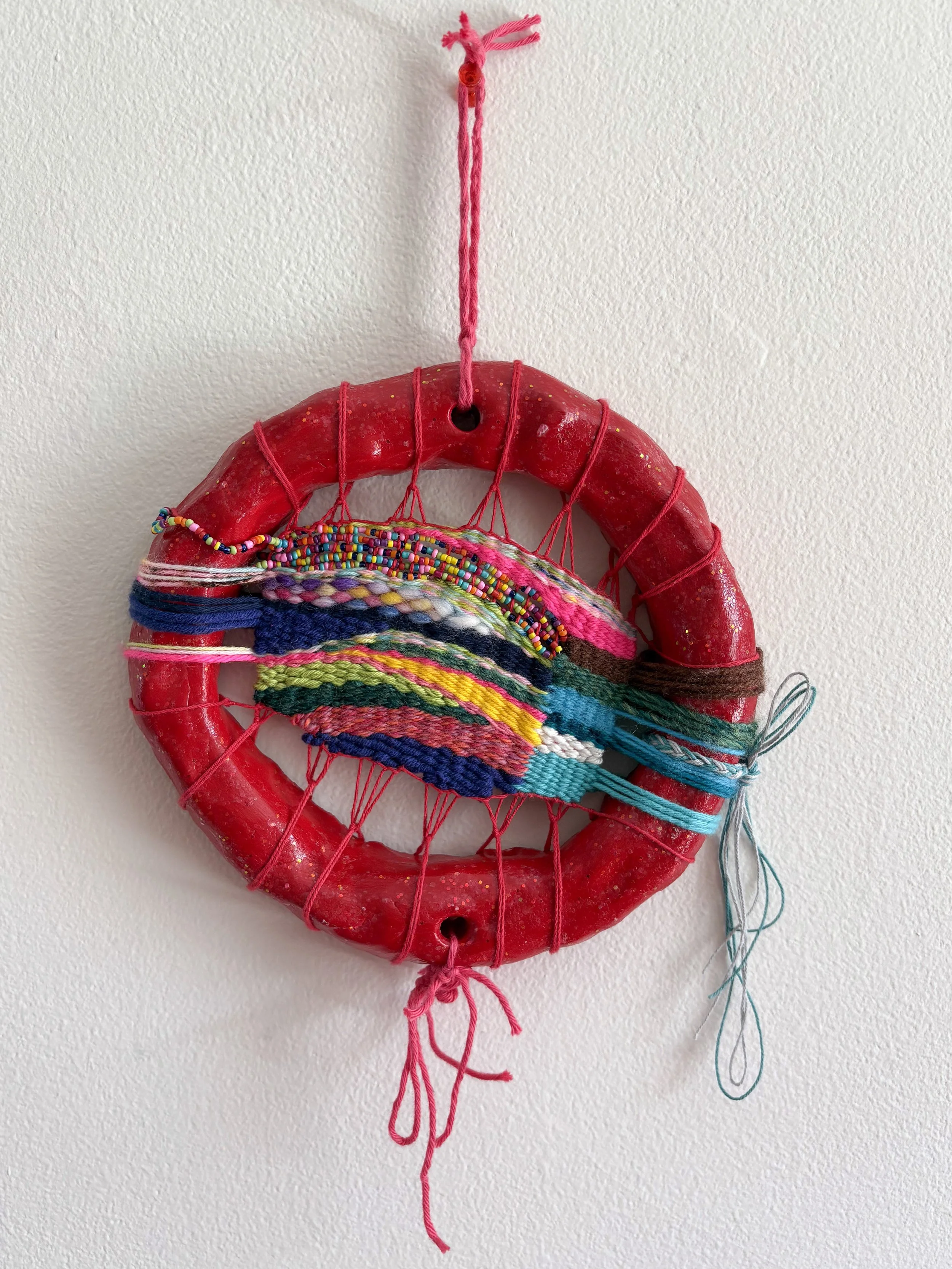 "Watching The Wizard of Oz in a hotel bed with the love of your life. A heart swelled with love and whimsy." --- Ruby Slippers (2026). 7.5" x 14" x 2". Thread, yarn, clay, wire, beads, acrylic paint, glitter, and glue. Available in shop.