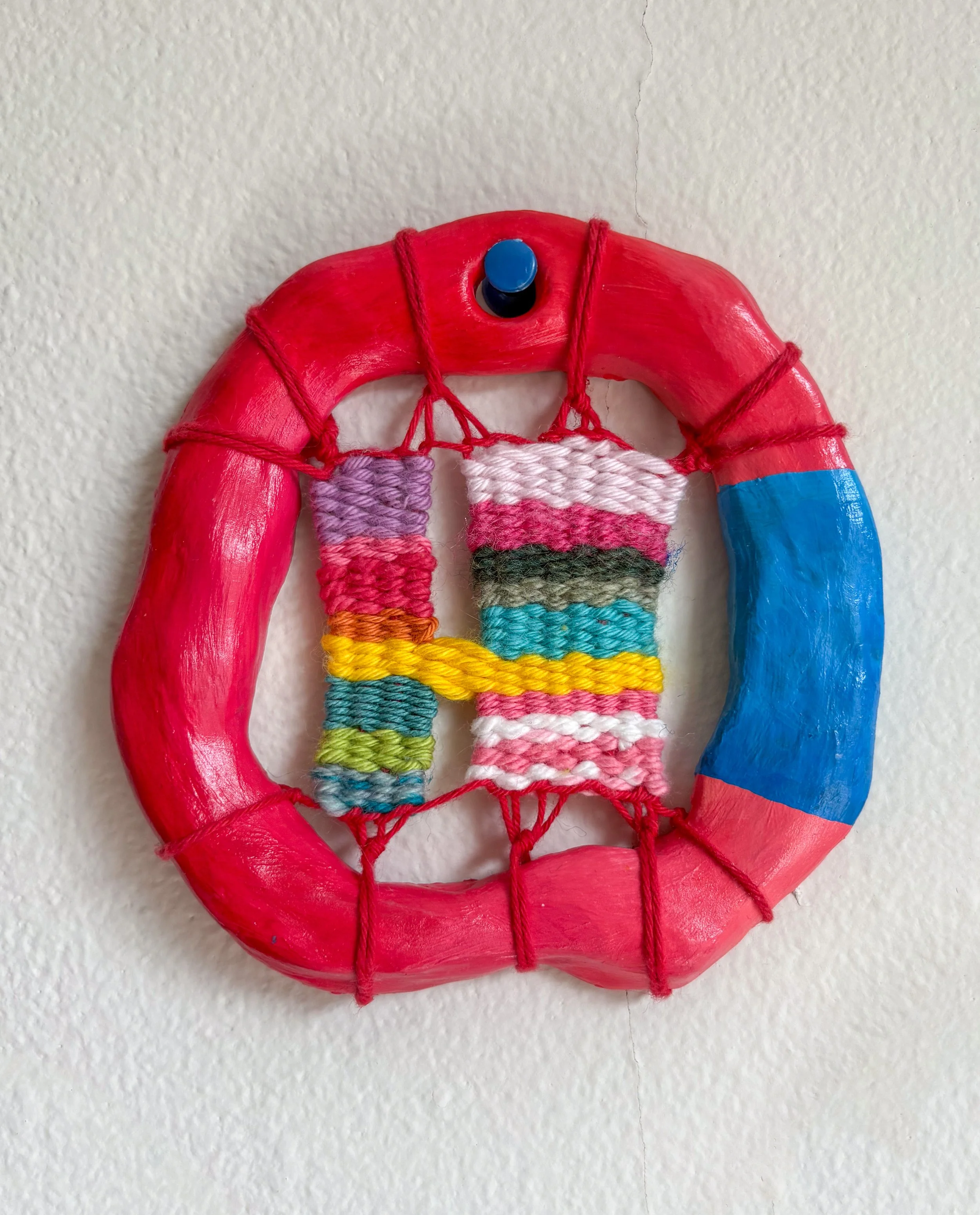 They're holding hands (2025). 4" x 4" x .5"	Thread, yarn, clay, acrylic paint, and glue.