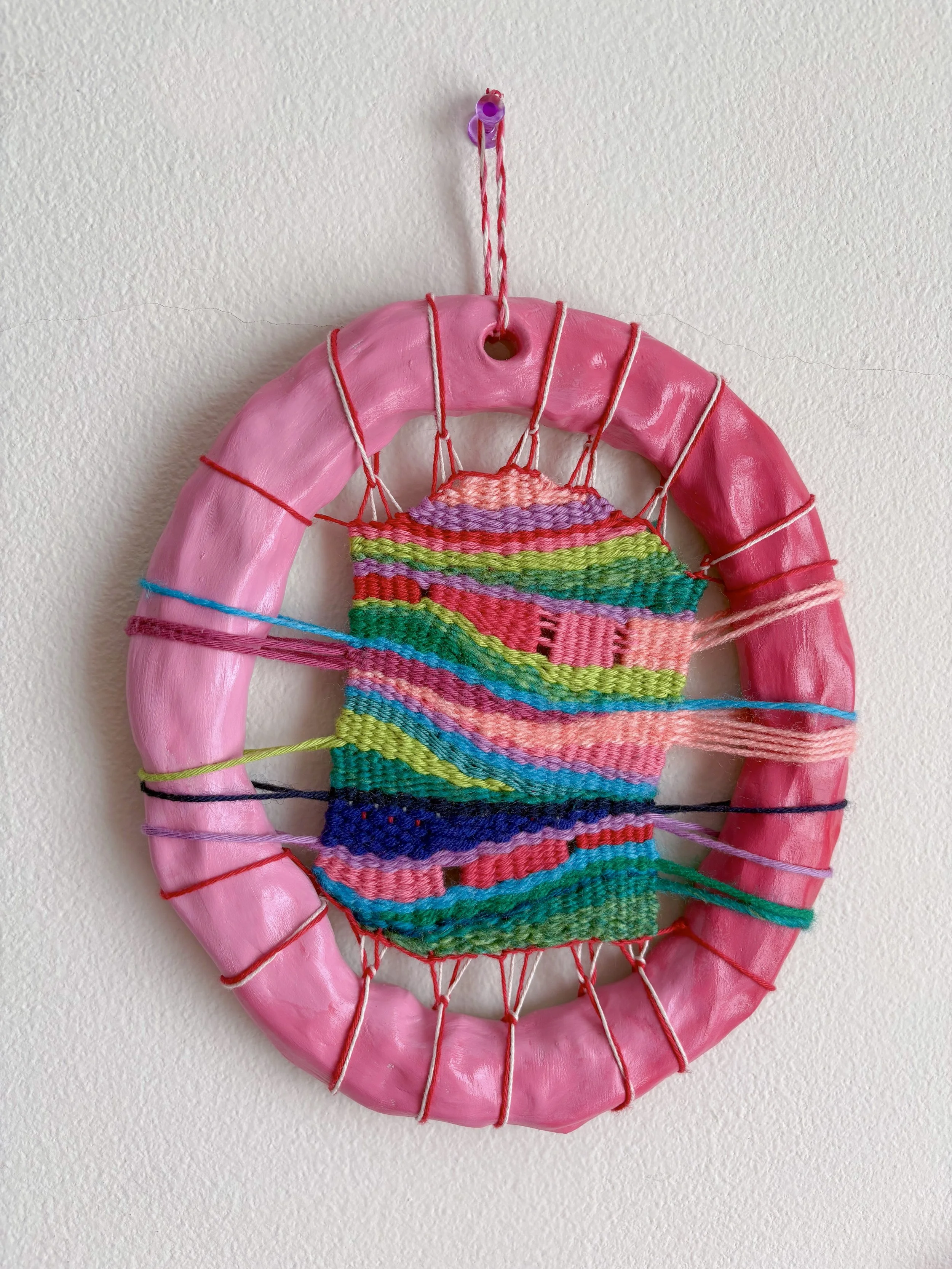 "Bubblegum mountains, pebbles by a river stream, and mixed berries fed to you by a lover on a picnic blanket. New versions of yourself that build upon the old. Forever growing." --- Growing (2025). 8" x 7" x 1". Thread, yarn, clay, acrylic paint, and