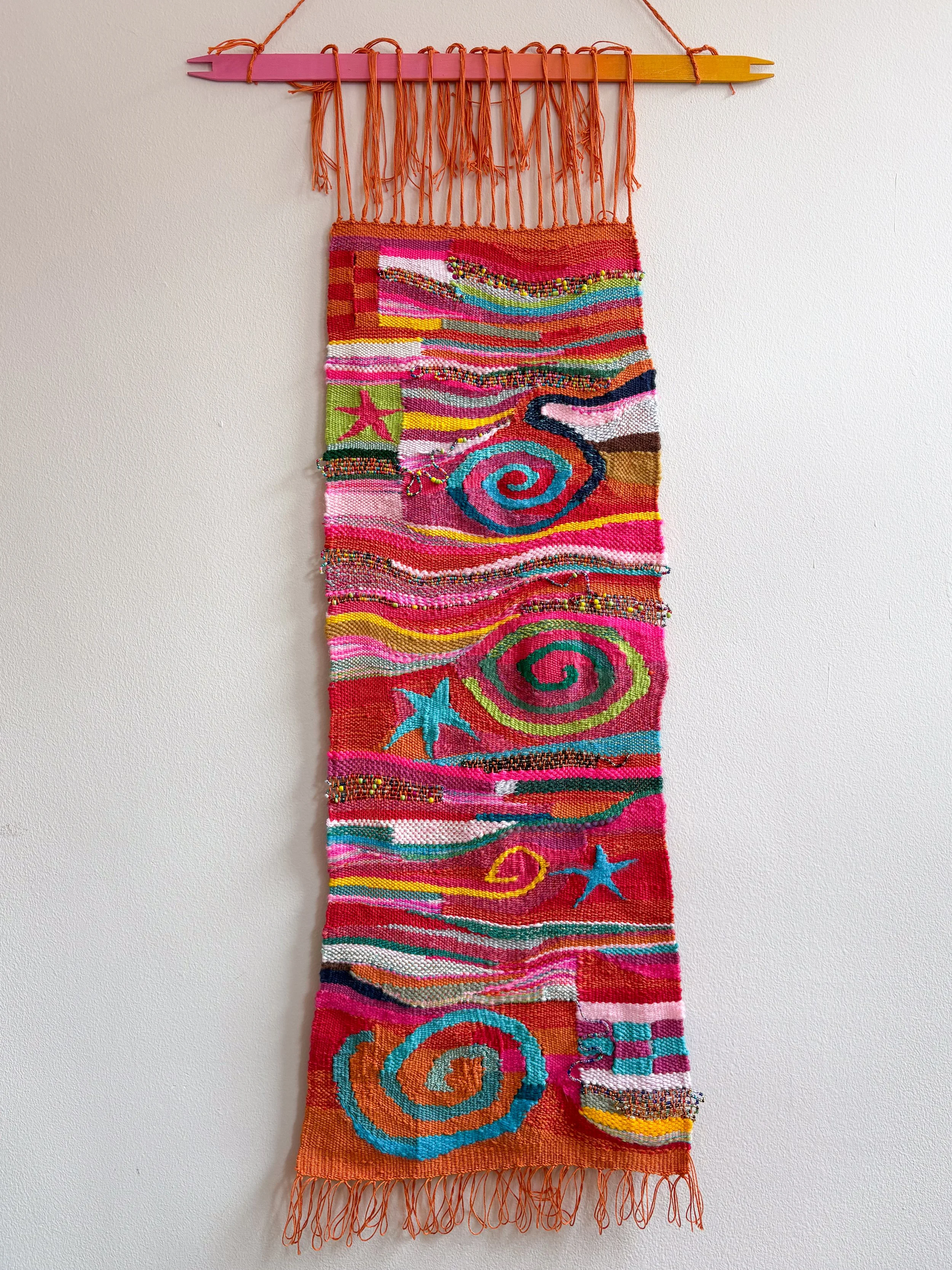 Oranges and Cinnamon, Spirals and Stars (2026). 11" x 31" x .45". Yarn, thread, beads, and wire.