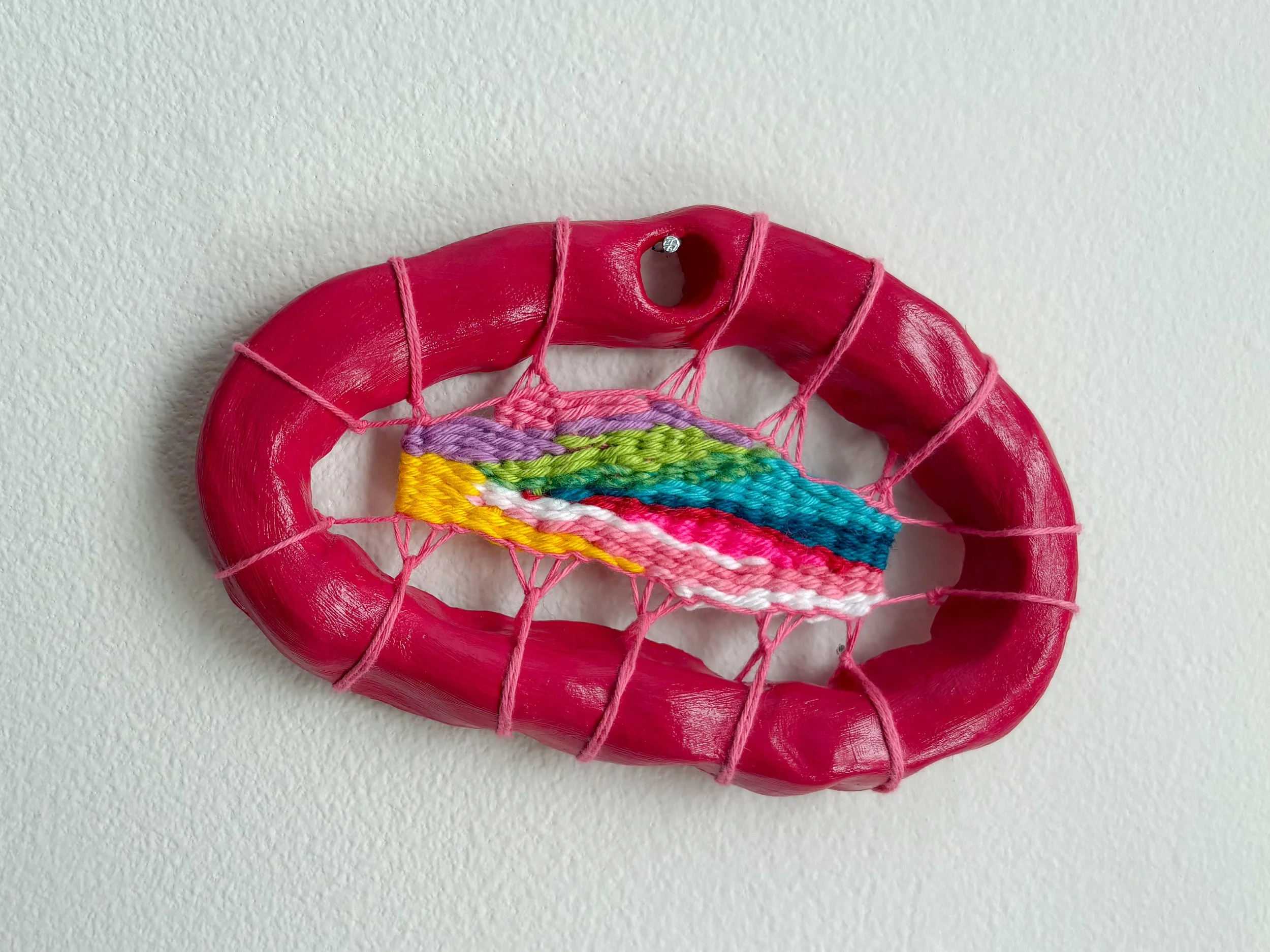 "Fresh-squeezed blood orange and strawberry juice. A geode cracked open to reveal unexpected colors." --- Strawberry Blood Orange (2025). 4" x 6" x .75". Thread, yarn, clay, acrylic paint, and glue. Available in shop.