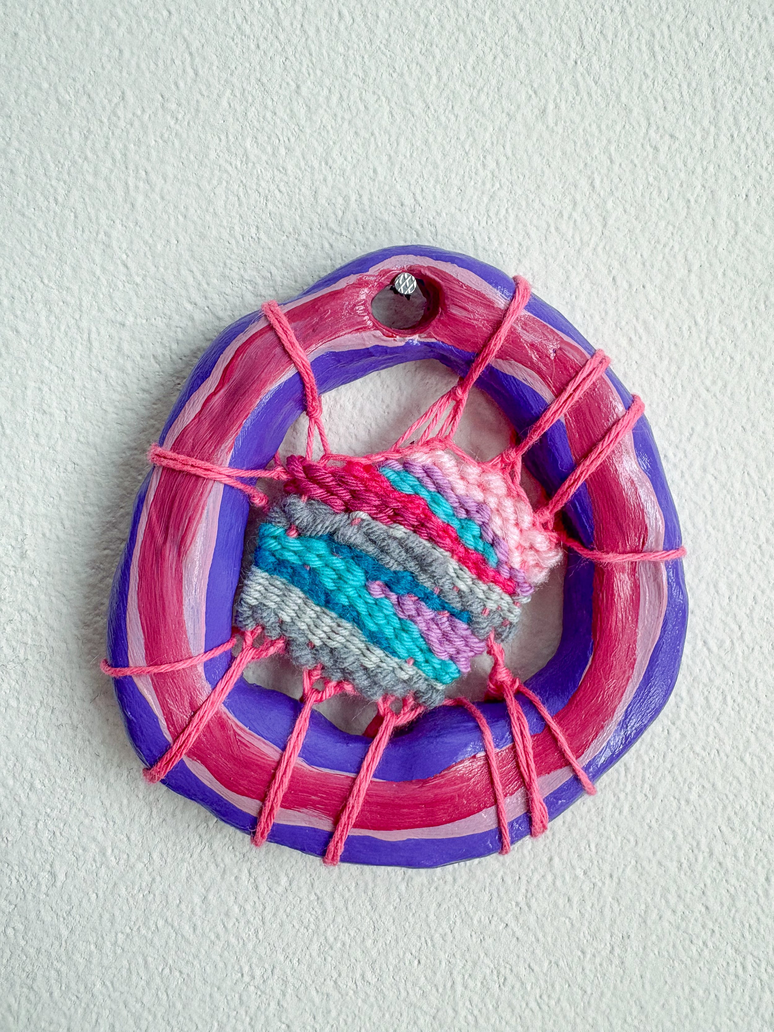 "A bisexual icon. Enough said." --- Bicon (2025). 3.25" x 3.5" x .75". Thread, yarn, clay, acrylic paint, and glue. Available in shop.