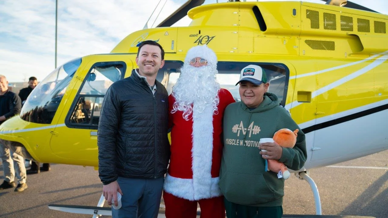 Denver Children’s Foundation member with a child and Santa in front of a helicopter at a Christmas for Kids event