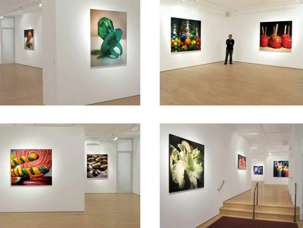 Views of an art gallery with various colorful photographs of objects, including jewelry, candies, flowers, and toys displayed on white walls.