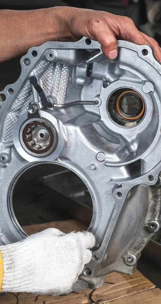 Close-up of a metallic engine part with a person's hand and glove in the process of assembling or inspecting it.